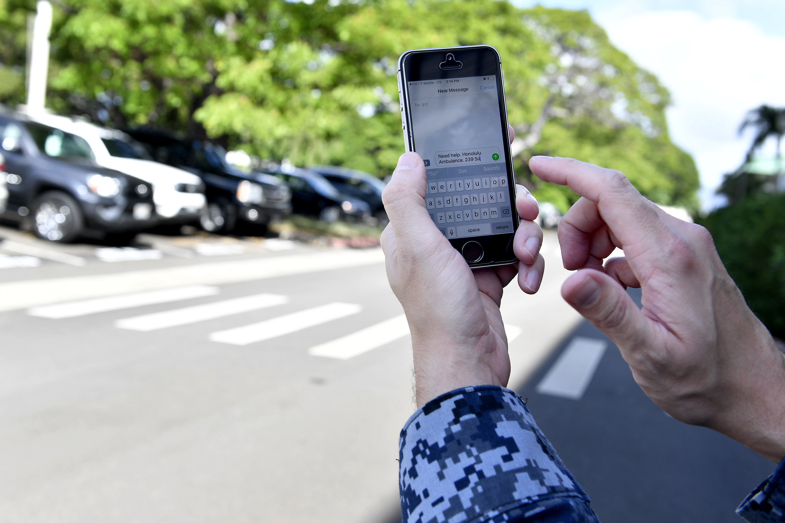 Person in camouflage uniform holds a smartphone displaying a text message compose screen.