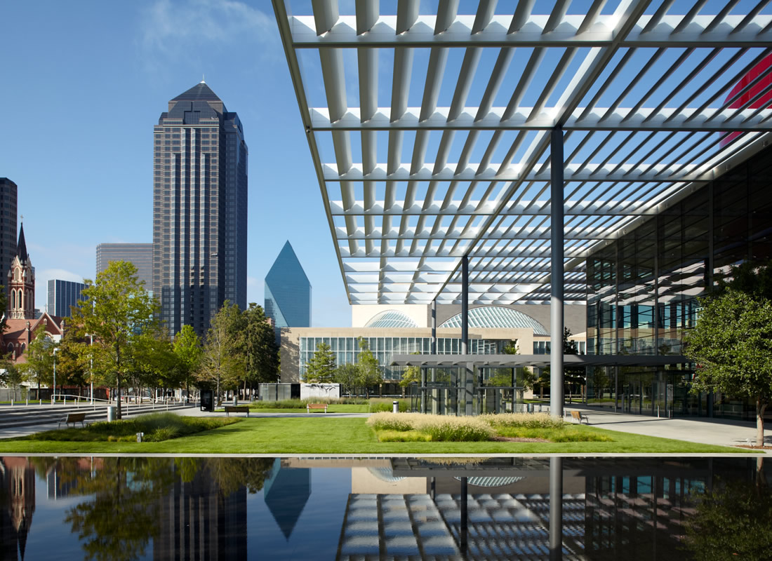 Downtown Dallas skyline with a reflecting pool in the foreground and multiple glass skyscrapers behind.