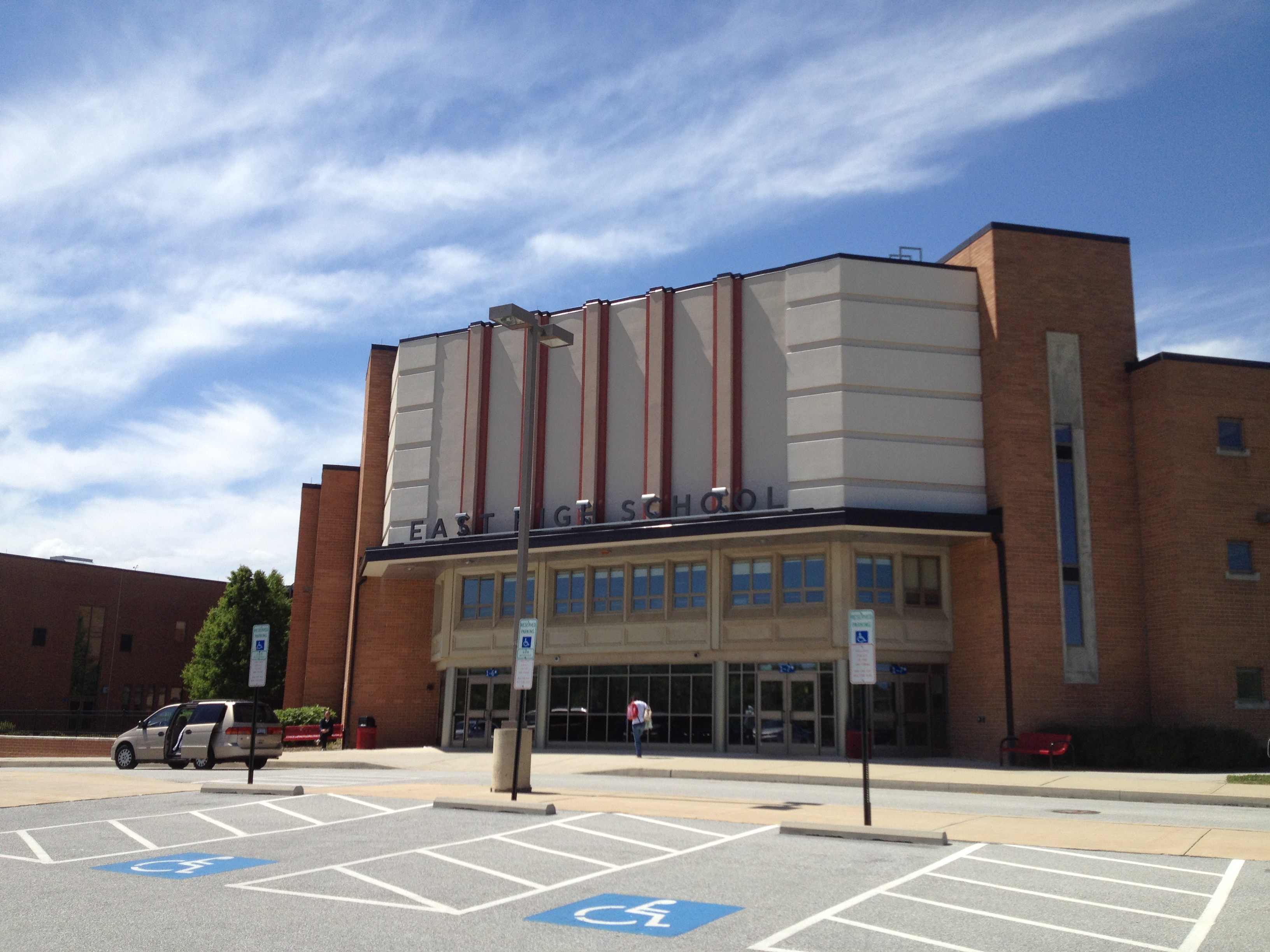 Brick exterior of East High School with handicap parking spaces in the foreground.
