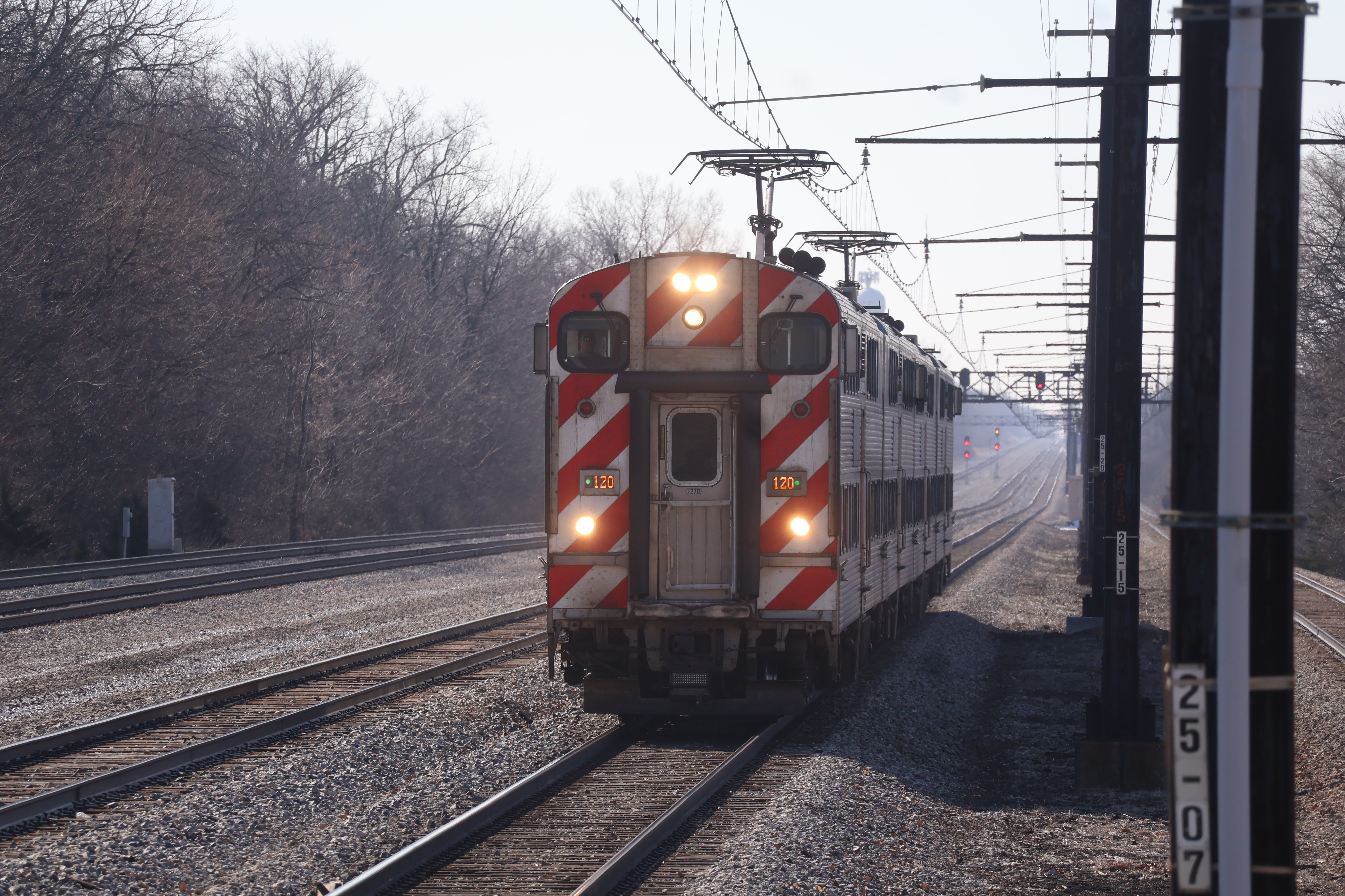 A Metra Electric commuter train approaches on tracks with overhead wires.
