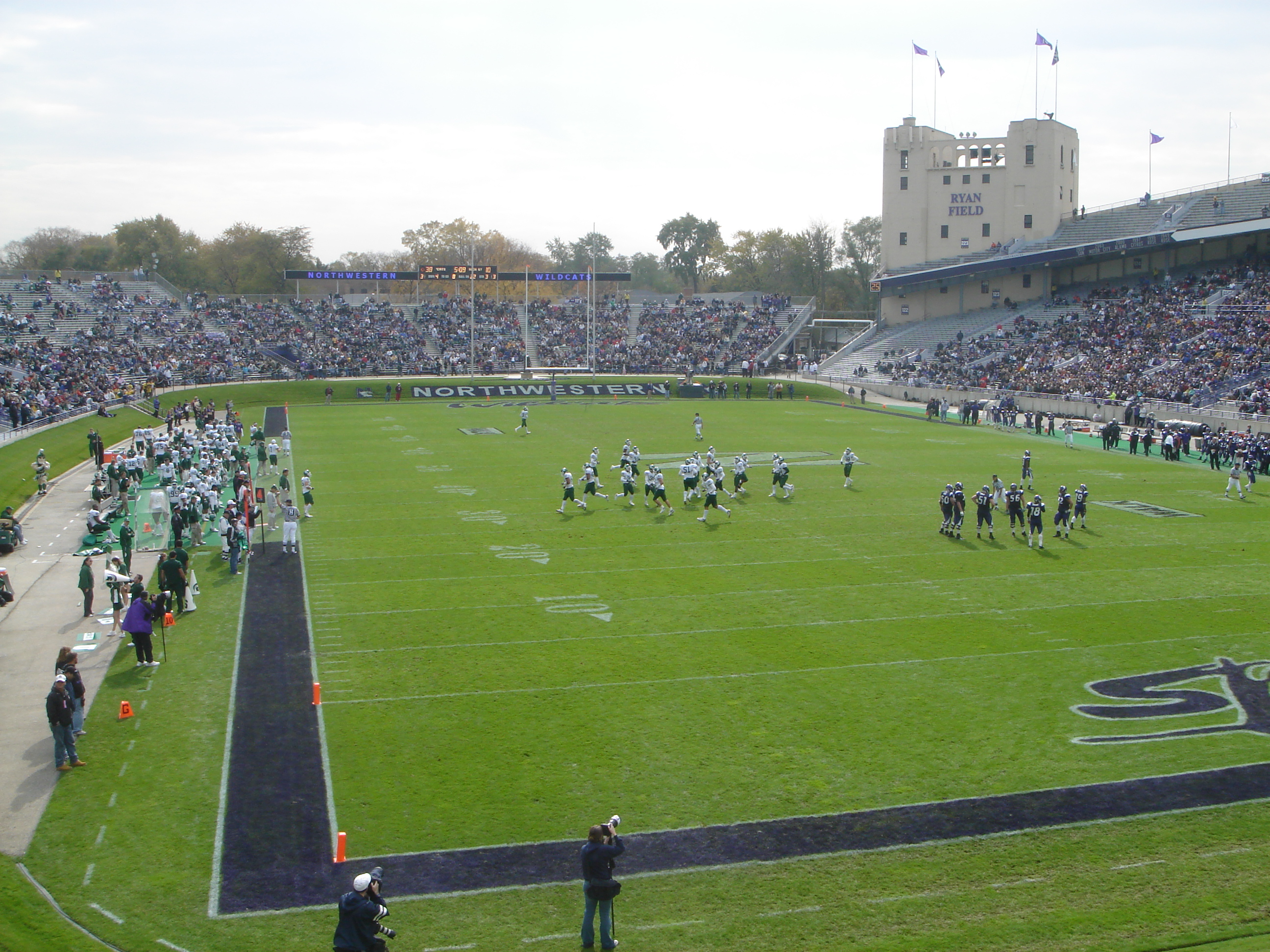 College football game in progress at Ryan Field with players on the field and packed grandstands.