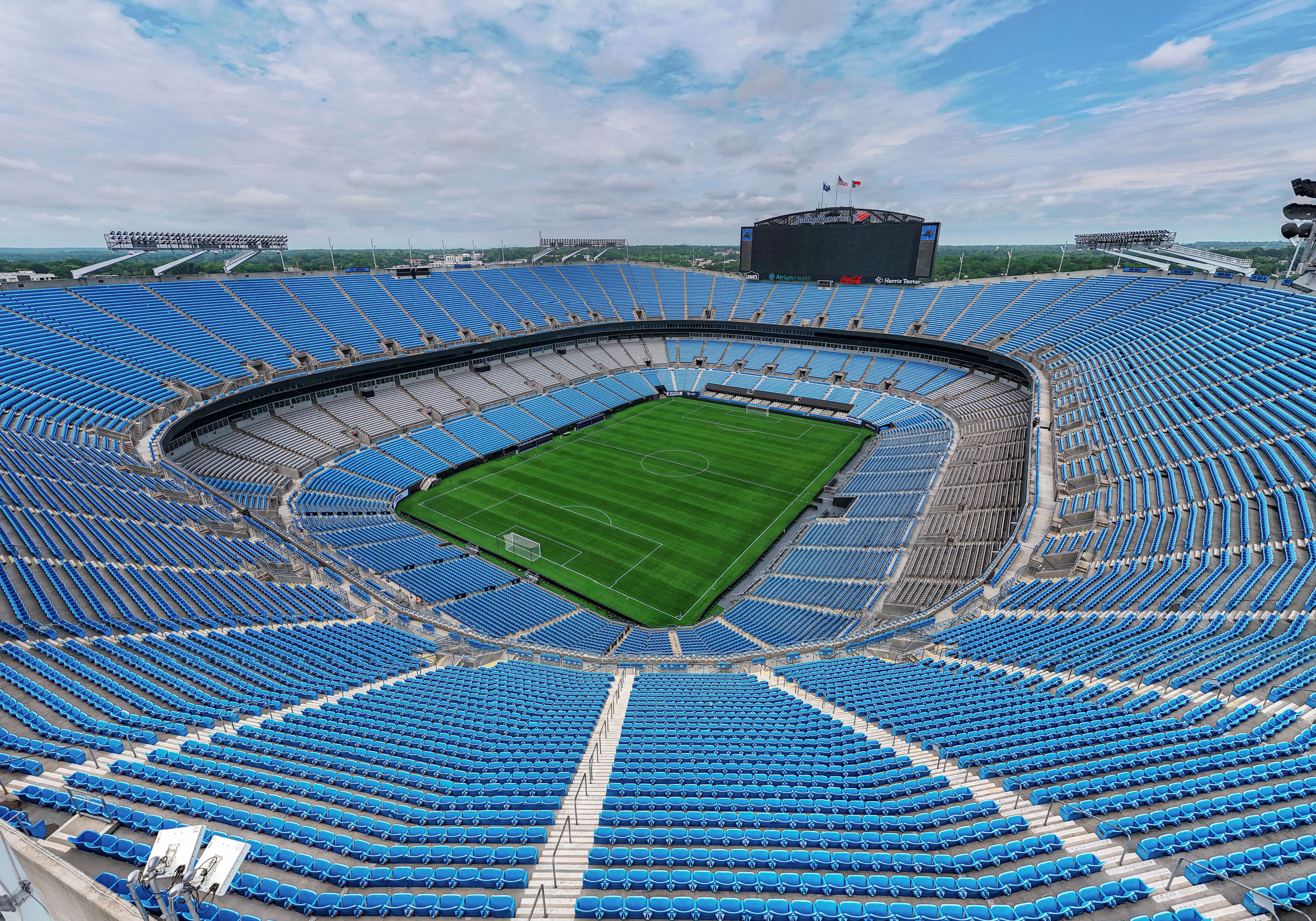 Aerial interior view of a large NFL stadium with blue seats and a green field.