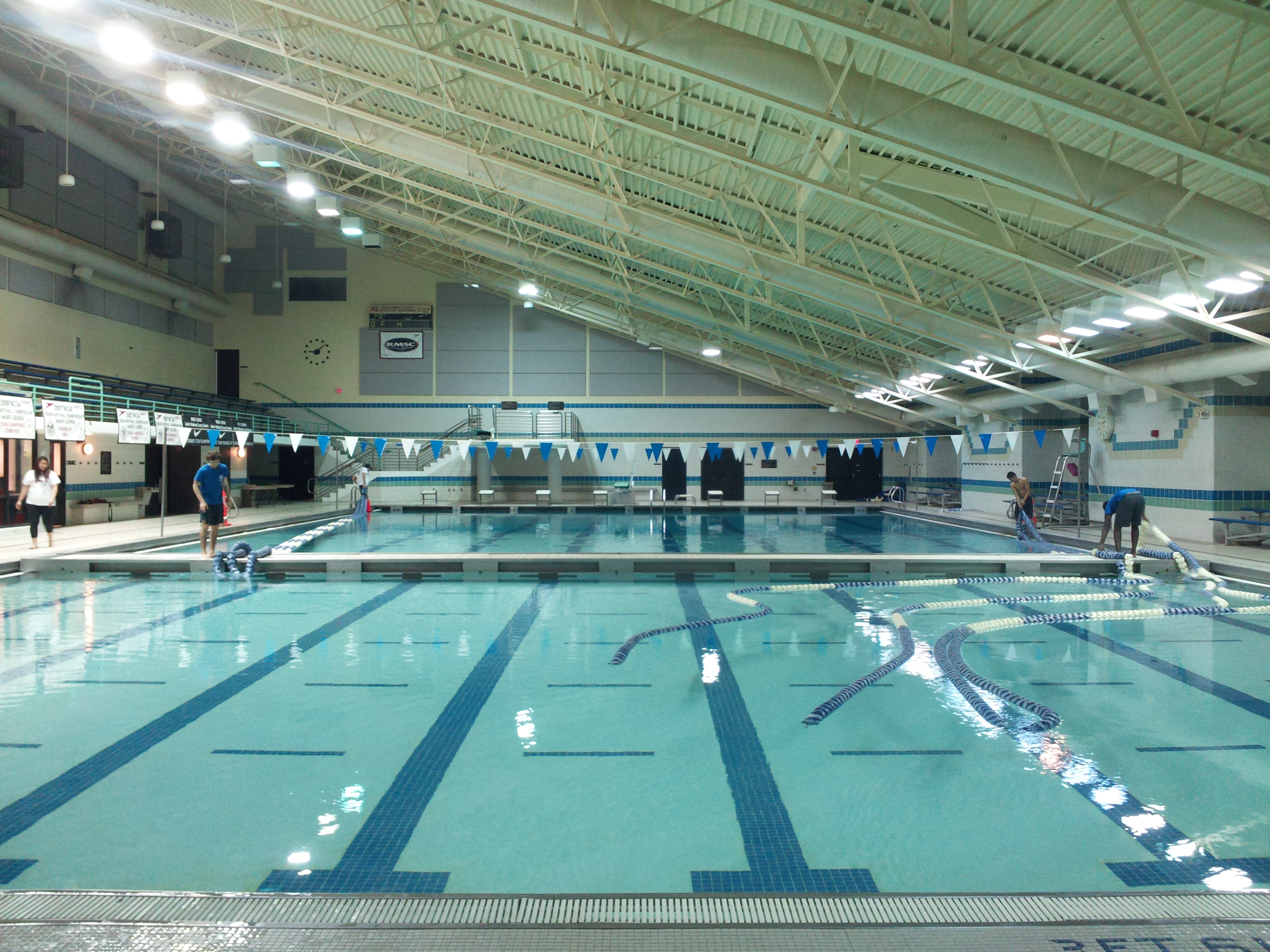 Indoor natatorium with lane ropes and pennant banners strung above a competition pool.