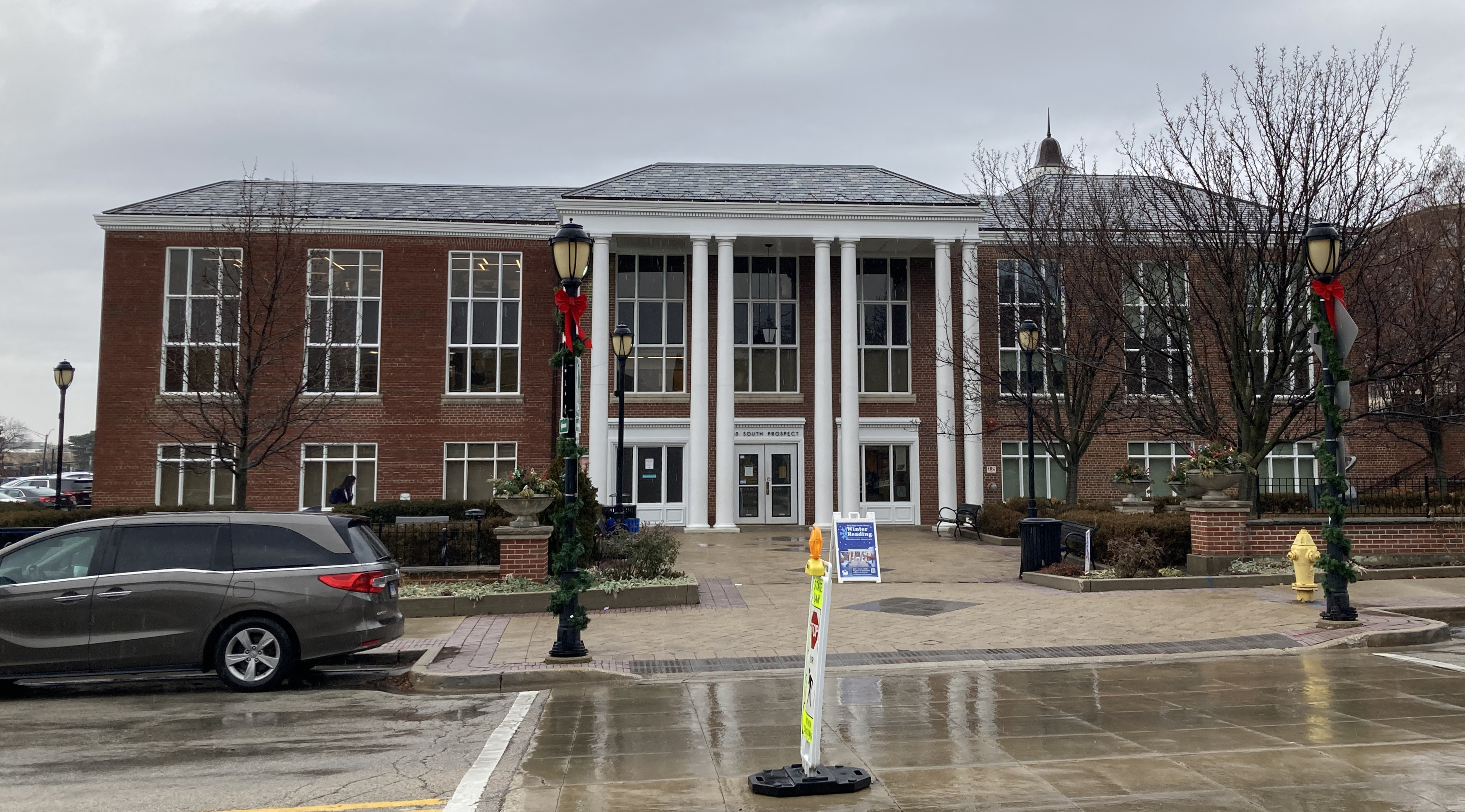 Exterior of a two-story brick library building with white columns on an overcast day.
