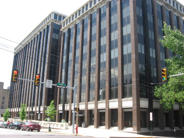 Multi-story brick and glass office building on a sunny street corner.