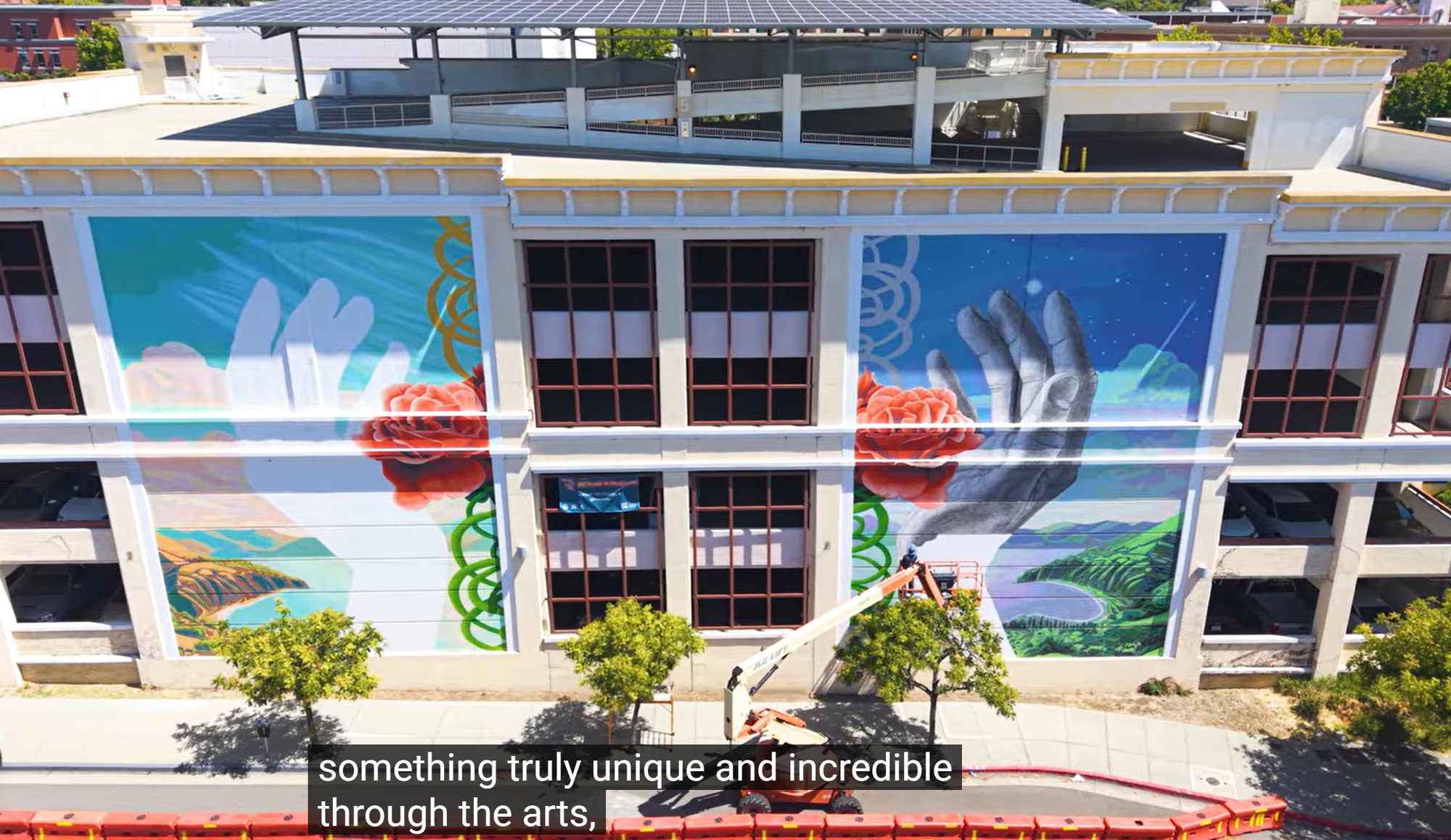 Large colorful mural of hands and roses covering a multi-story building exterior.