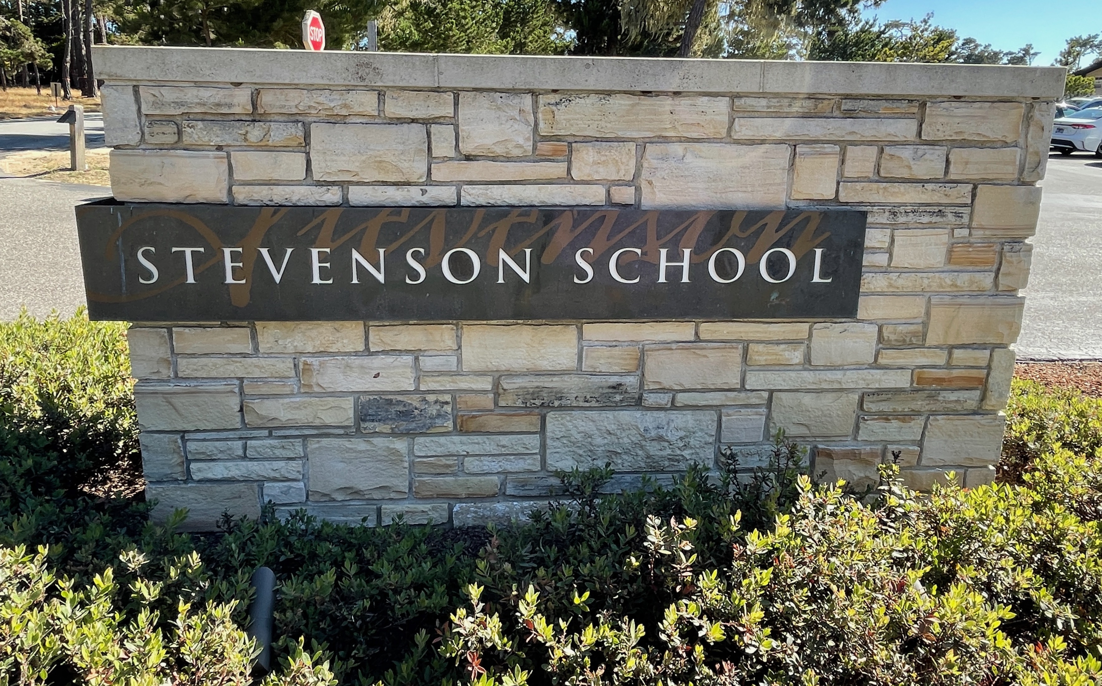 Stone entrance sign reading Stevenson School with shrubs and trees in the background.