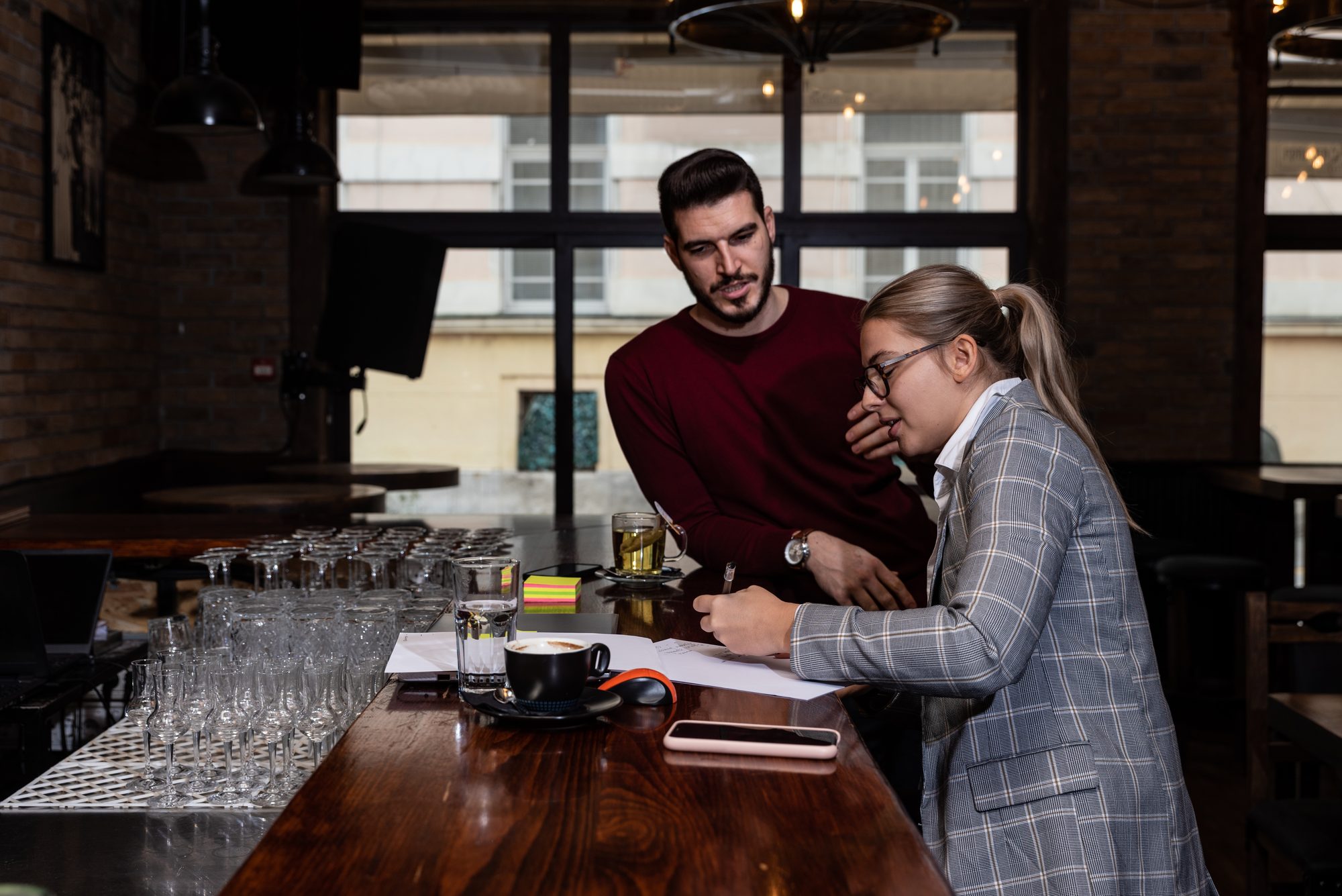 Health inspector sitting in a restaurant and writes a fine and a negative report to the owner or manager of the cafeteria after she finds poor hygiene conditions in the kitchen. Sanitary inspection