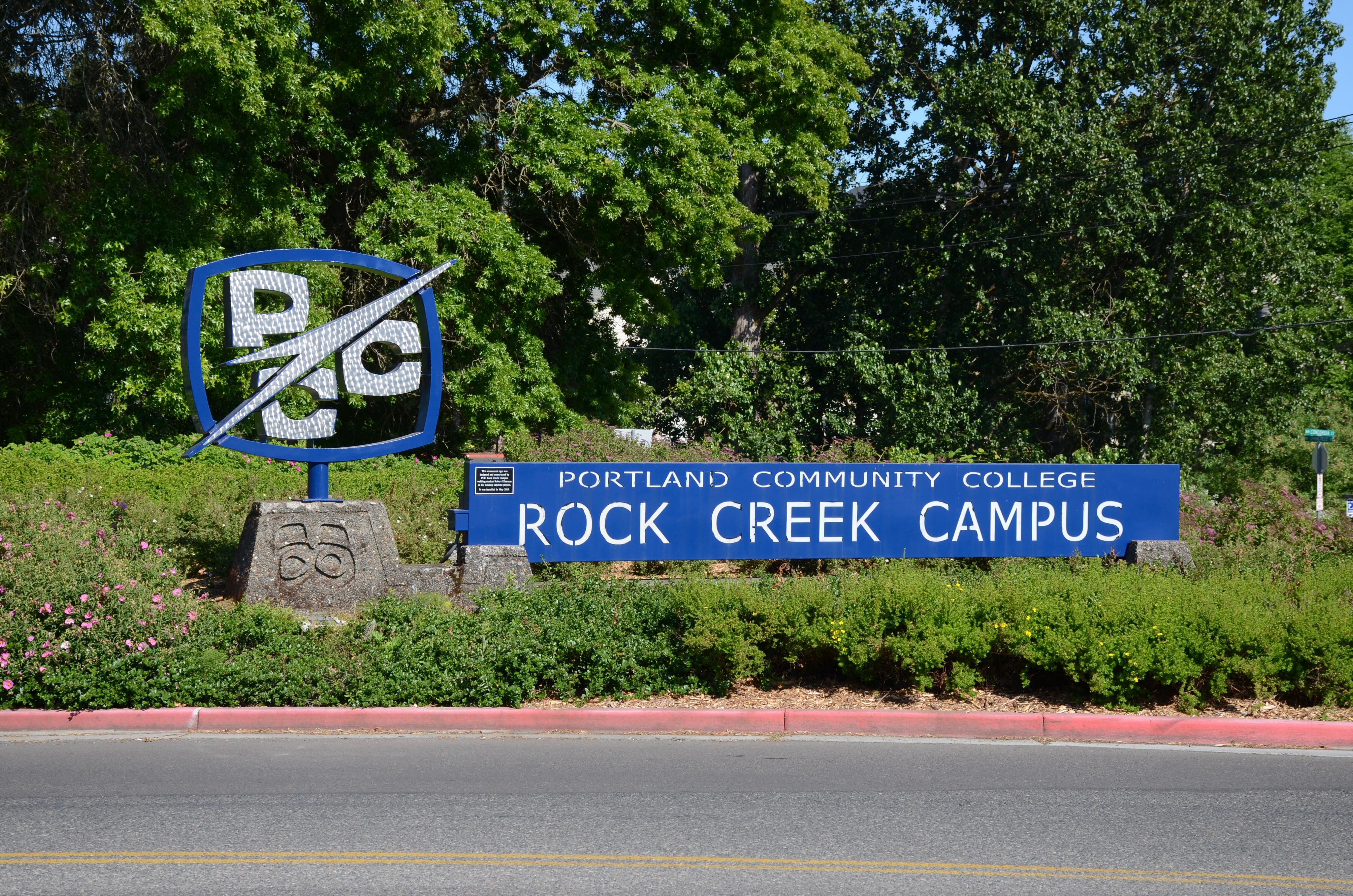 Blue entrance sign for Portland Community College Rock Creek Campus surrounded by trees.