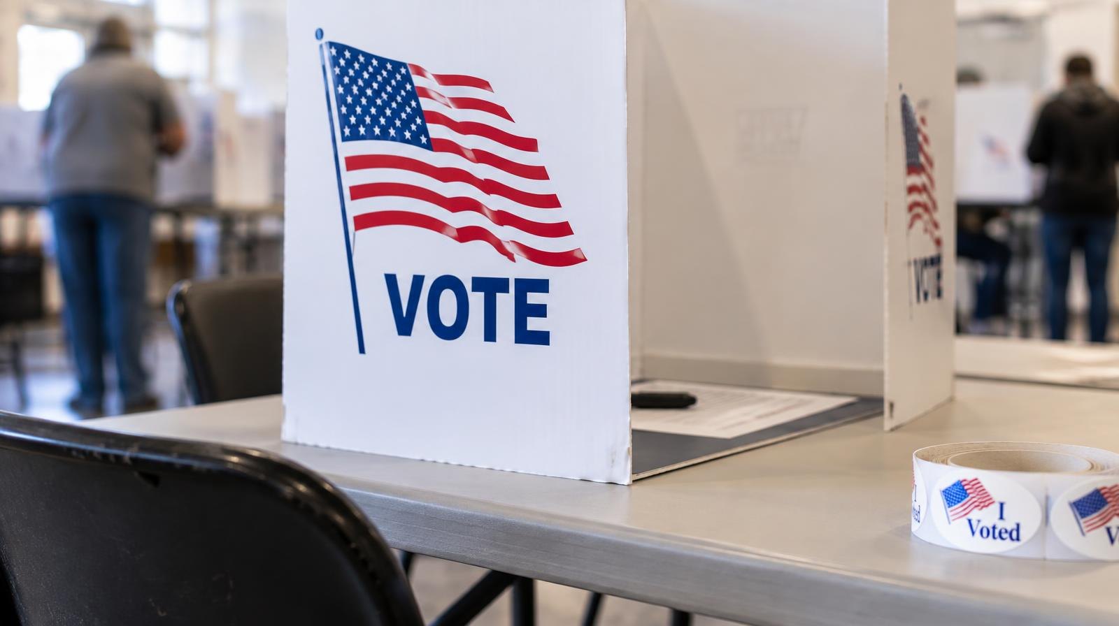 A portable voting booth on a folding table under fluorescent lights.