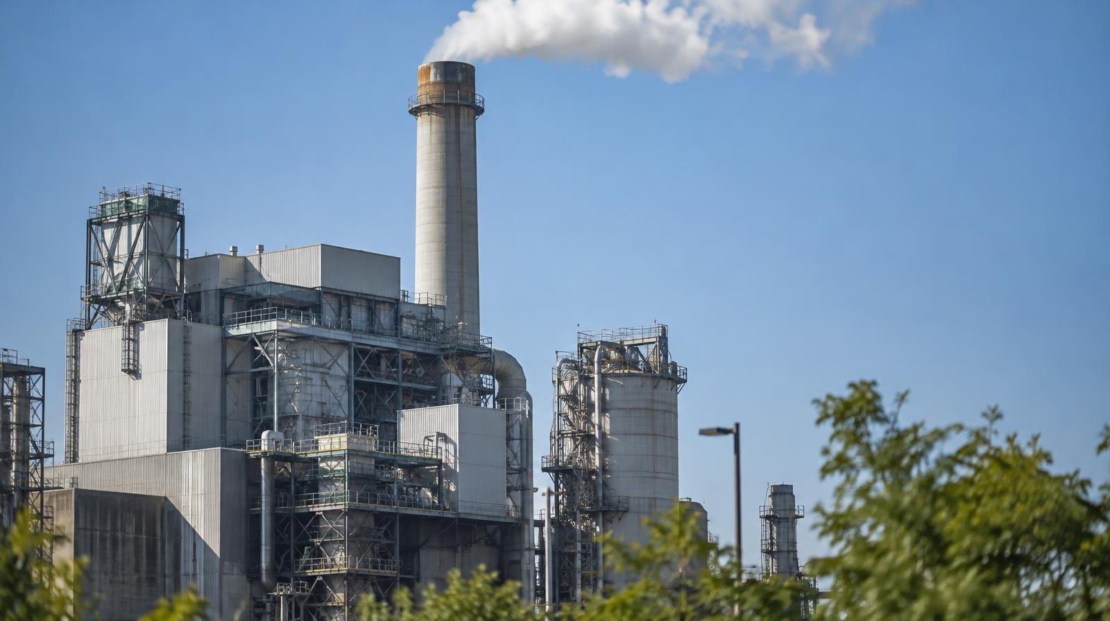 Industrial waste-to-energy facility with a tall smokestack against a clear sky.