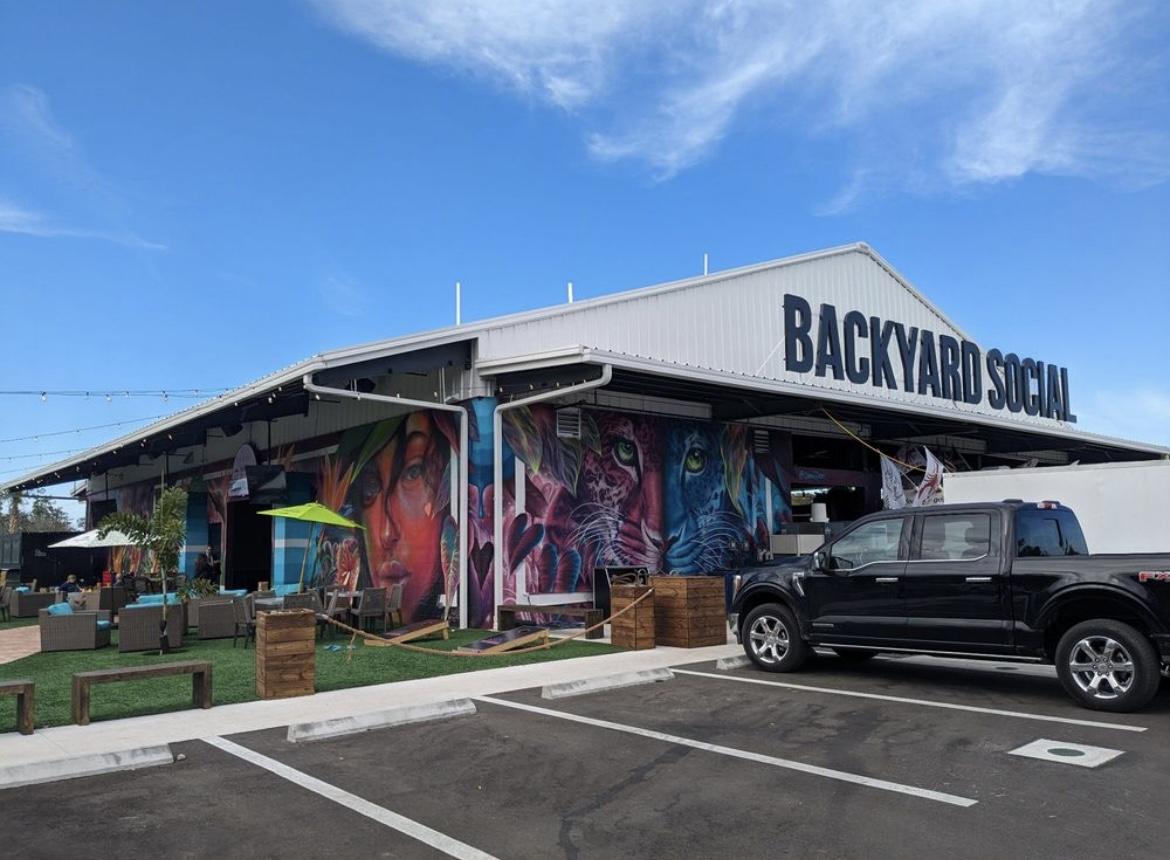 Exterior of Backyard Social in Fort Myers, featuring the venue’s large sign and colorful mural on the front of the building.