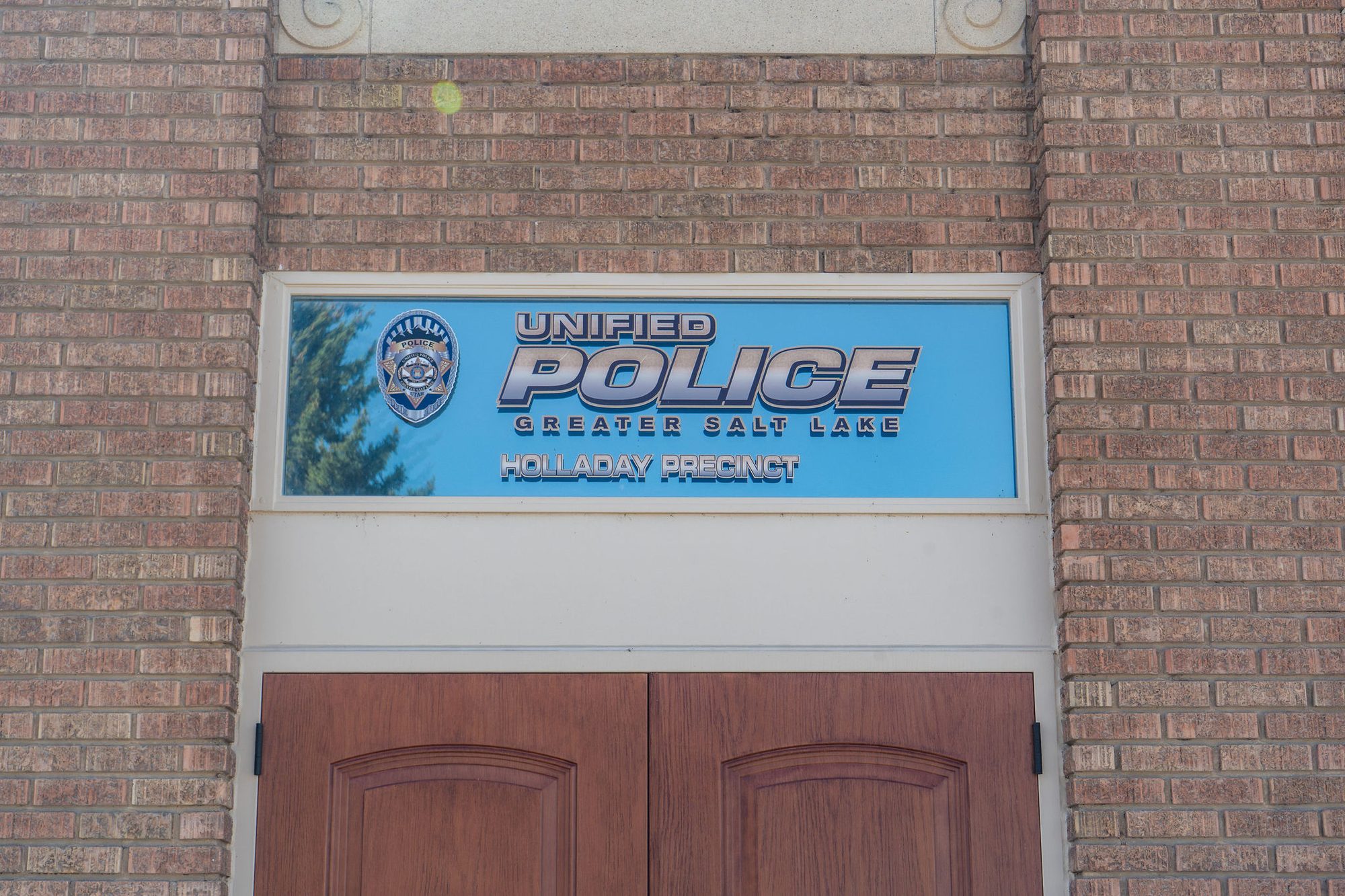 Brick building entrance with a police precinct sign above double doors.
