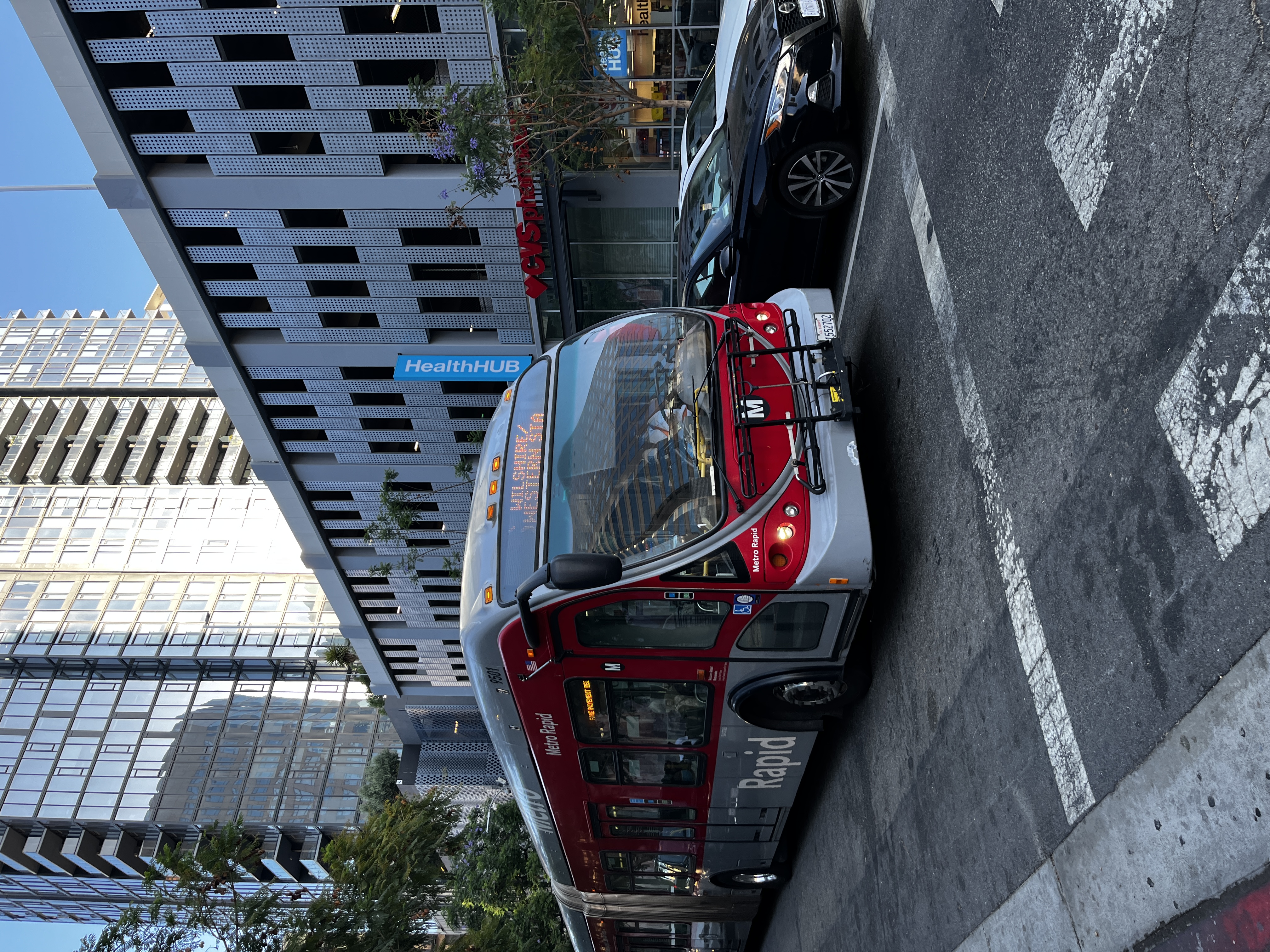 Red articulated Metro Rapid bus at a Los Angeles urban intersection.