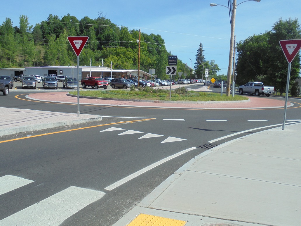 Aerial view of a completed roundabout with yield signs and a central grass island.