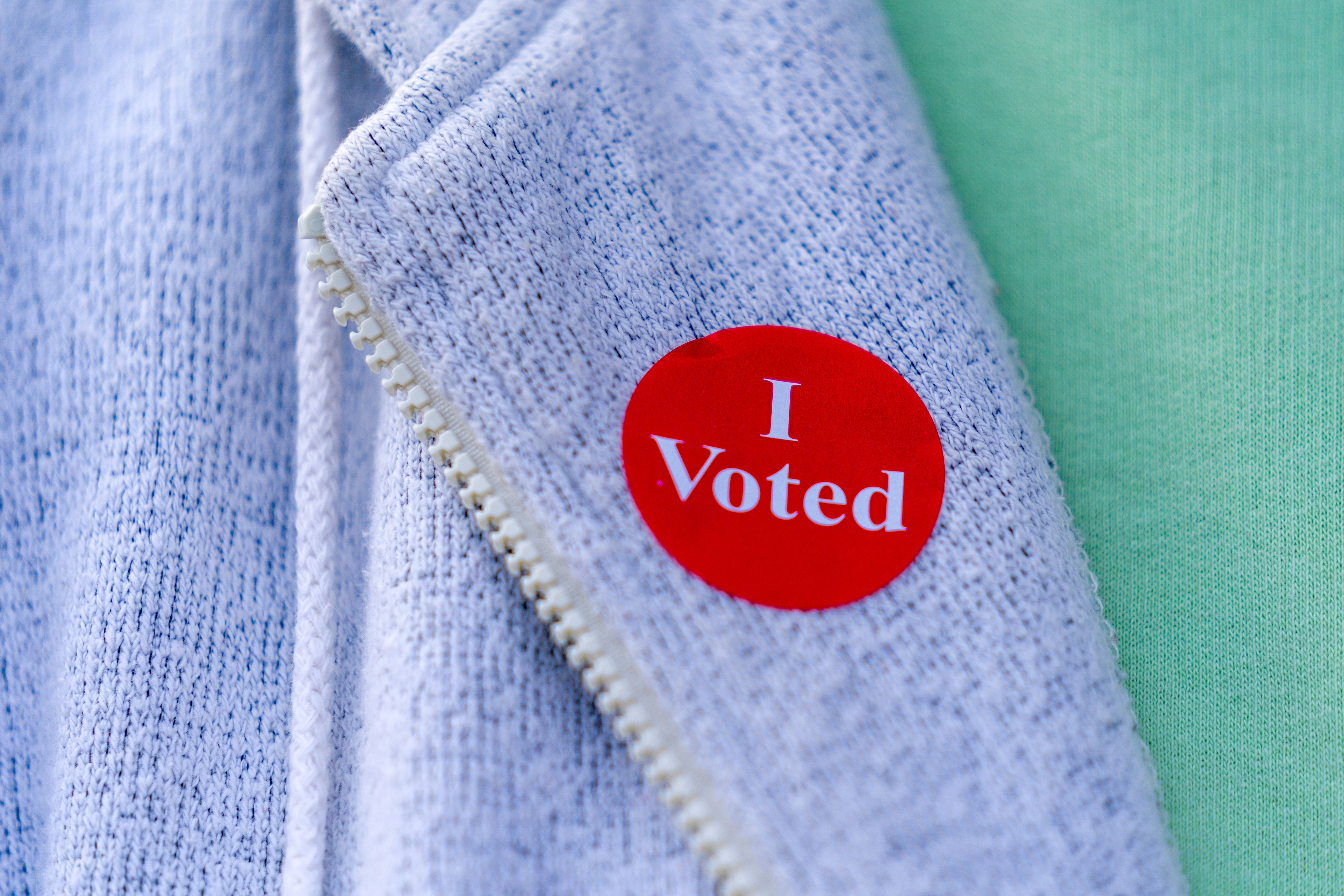 A red circular 'I Voted' sticker affixed to a light blue jacket.