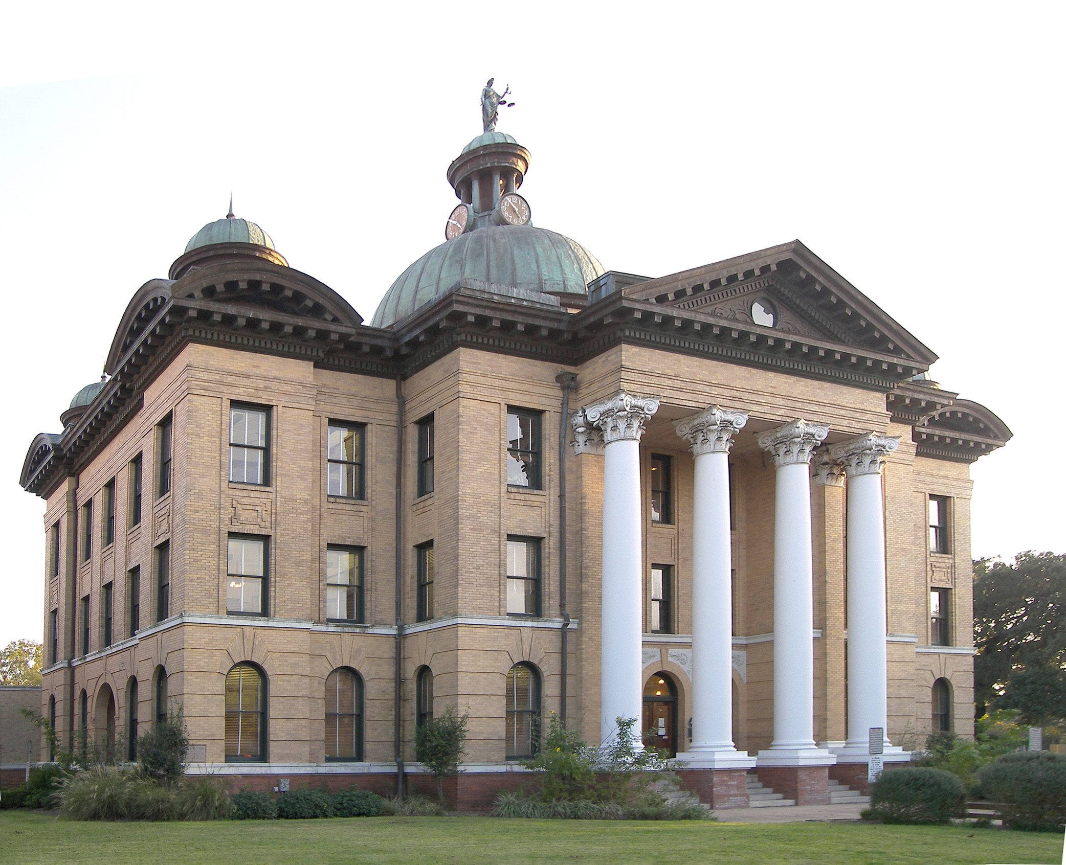 Beaux-Arts courthouse with white columns, green copper domes, and a statue on top, surrounded by a lawn.