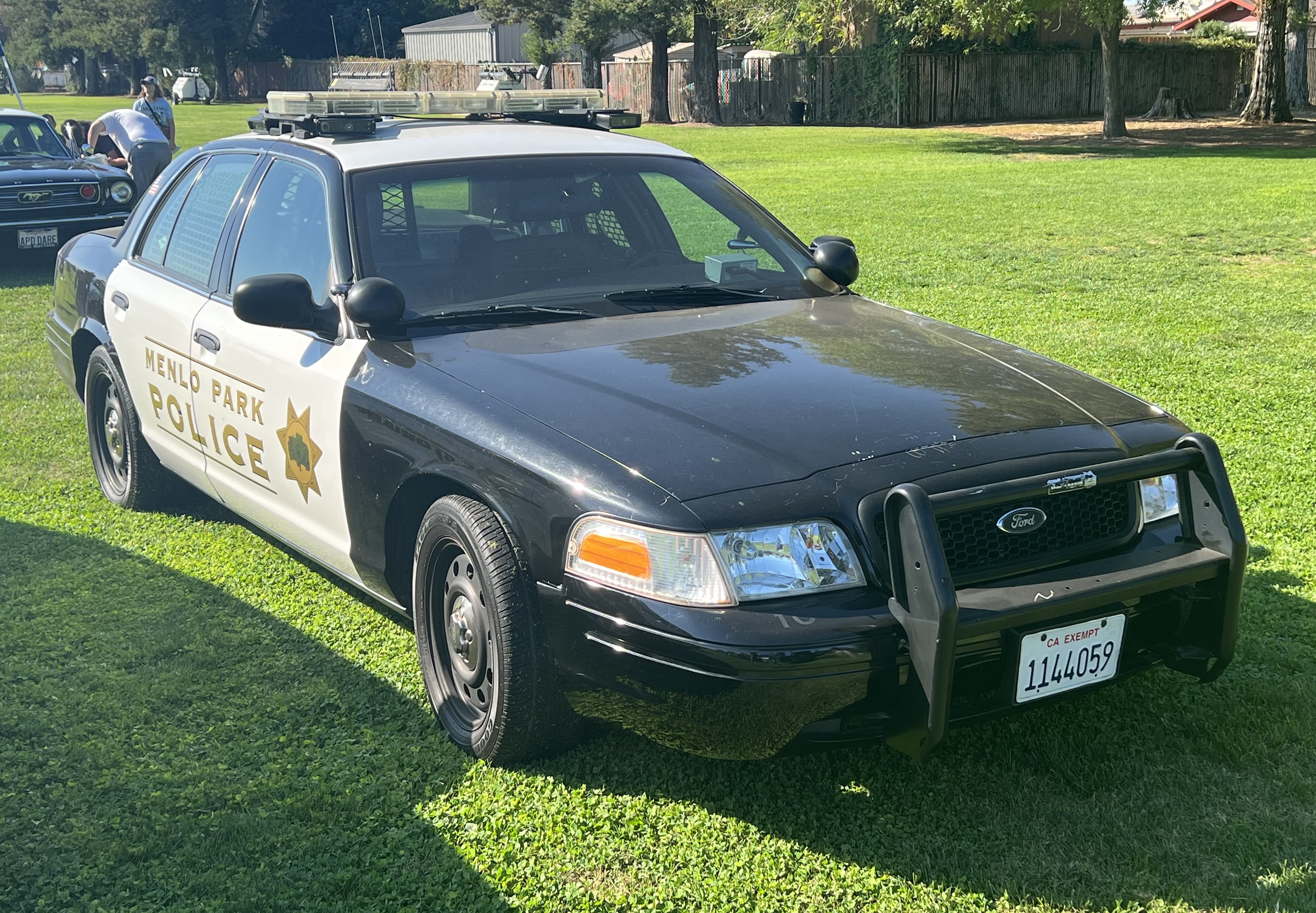 A black-and-white police cruiser marked Menlo Park Police parked on a grass lawn.
