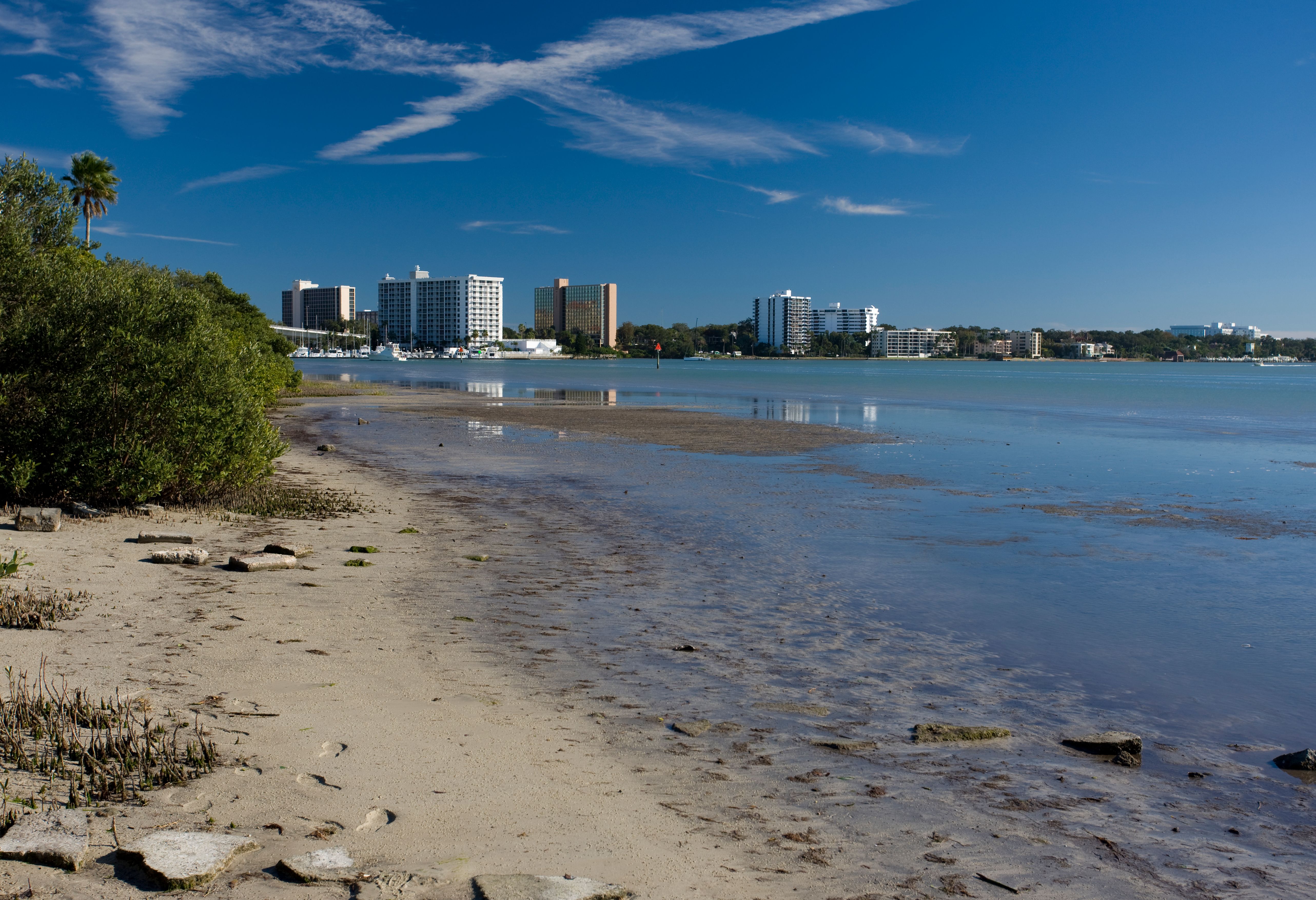 Sandy shoreline with calm water and a row of resort hotels along the beach.