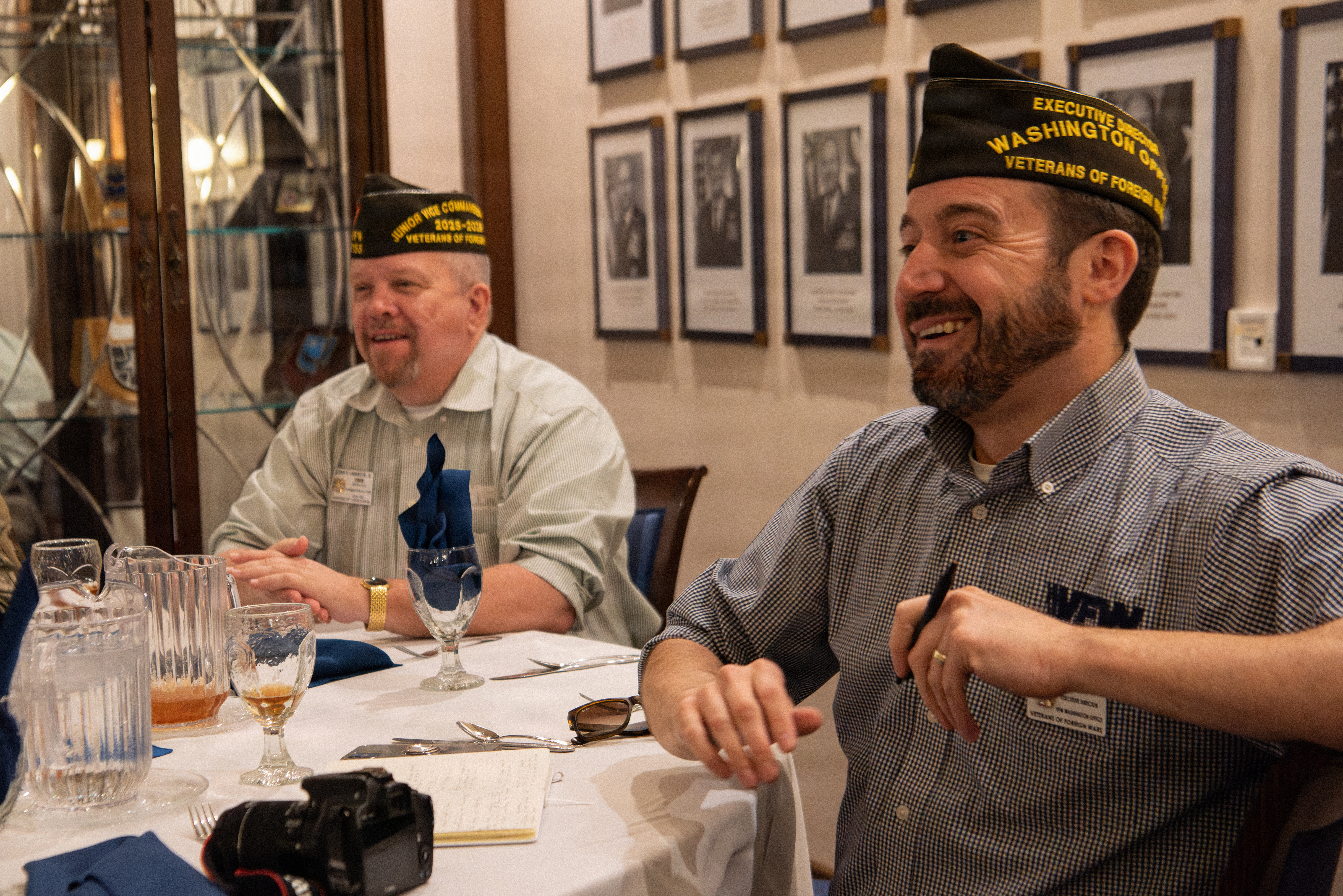 Two men wearing VFW garrison caps seated at a formal dining table.