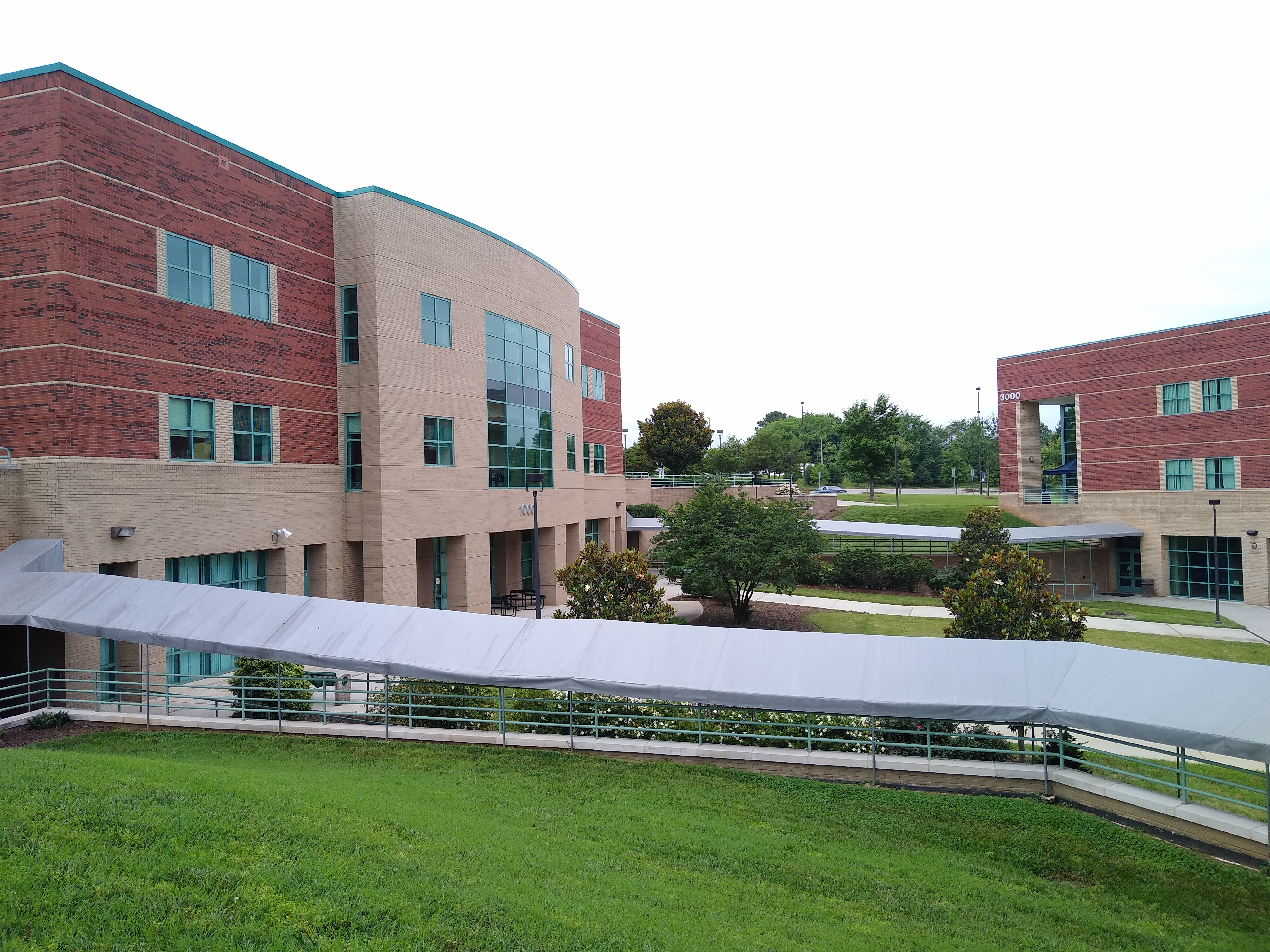 Multi-story brick college buildings with a covered walkway and landscaped courtyard.