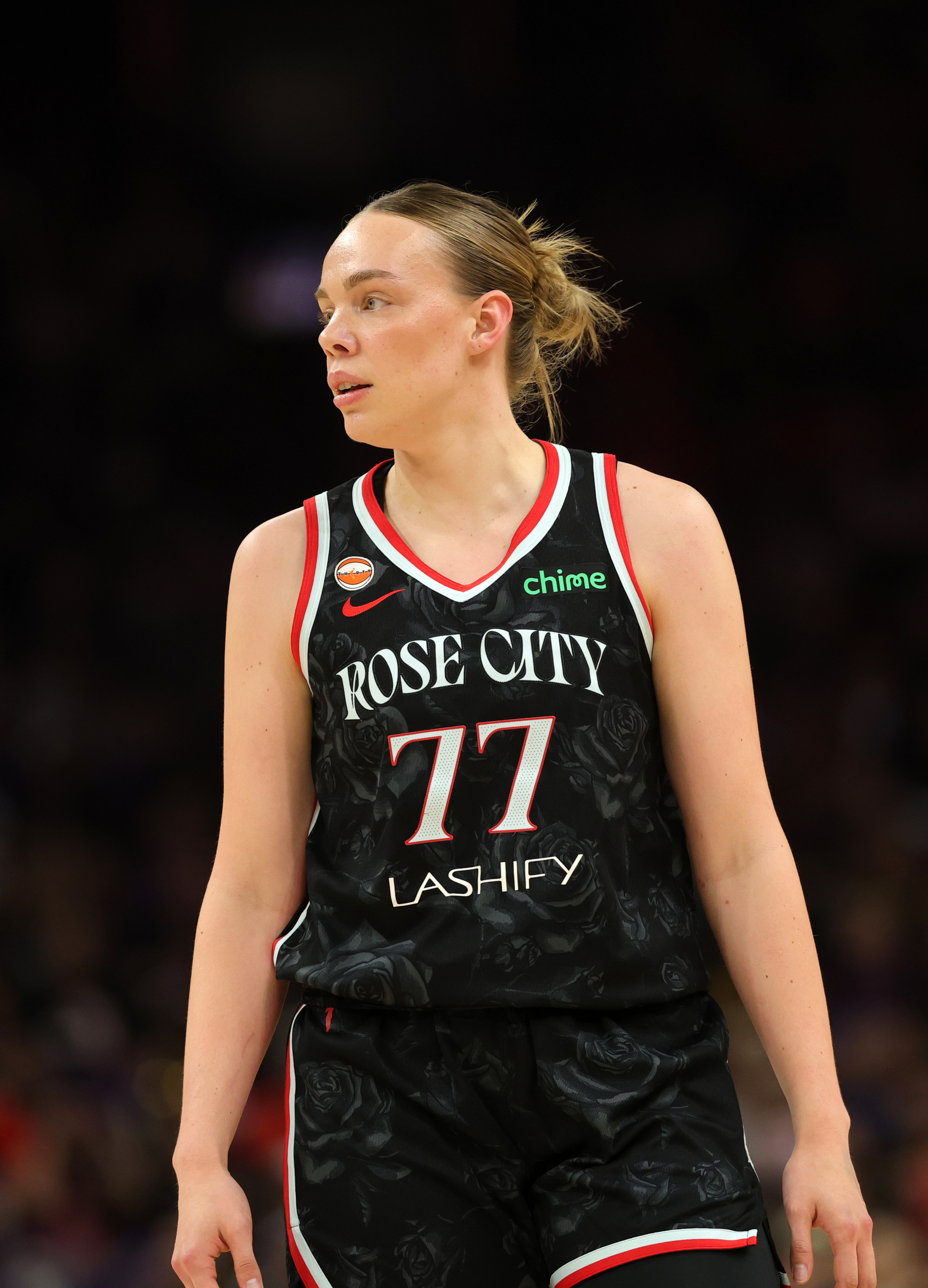 Portland Fire player in a black Rose City jersey stands on a basketball court during a game.
