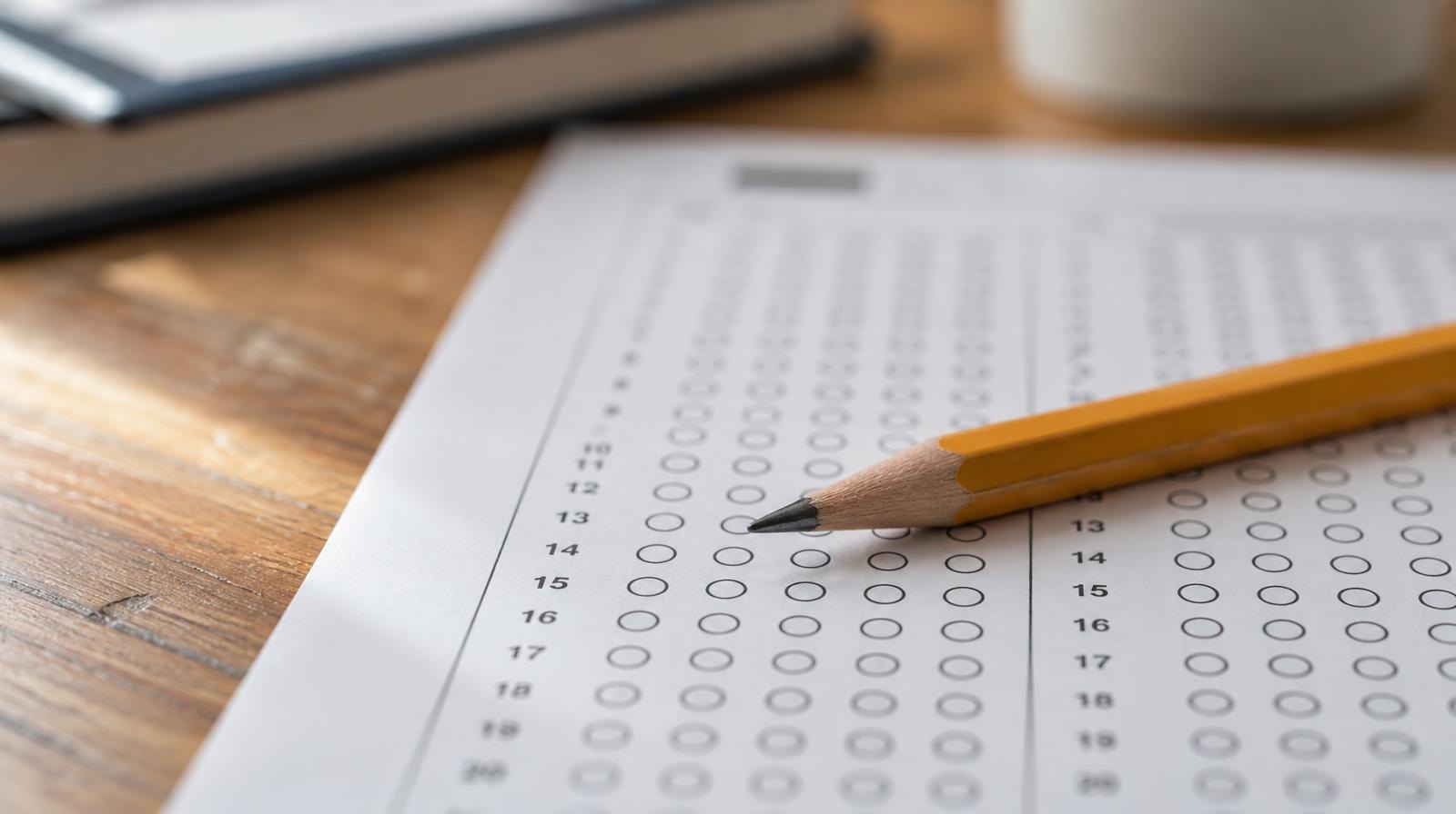 A sharpened pencil resting on a blank answer sheet with rows of empty bubbles.