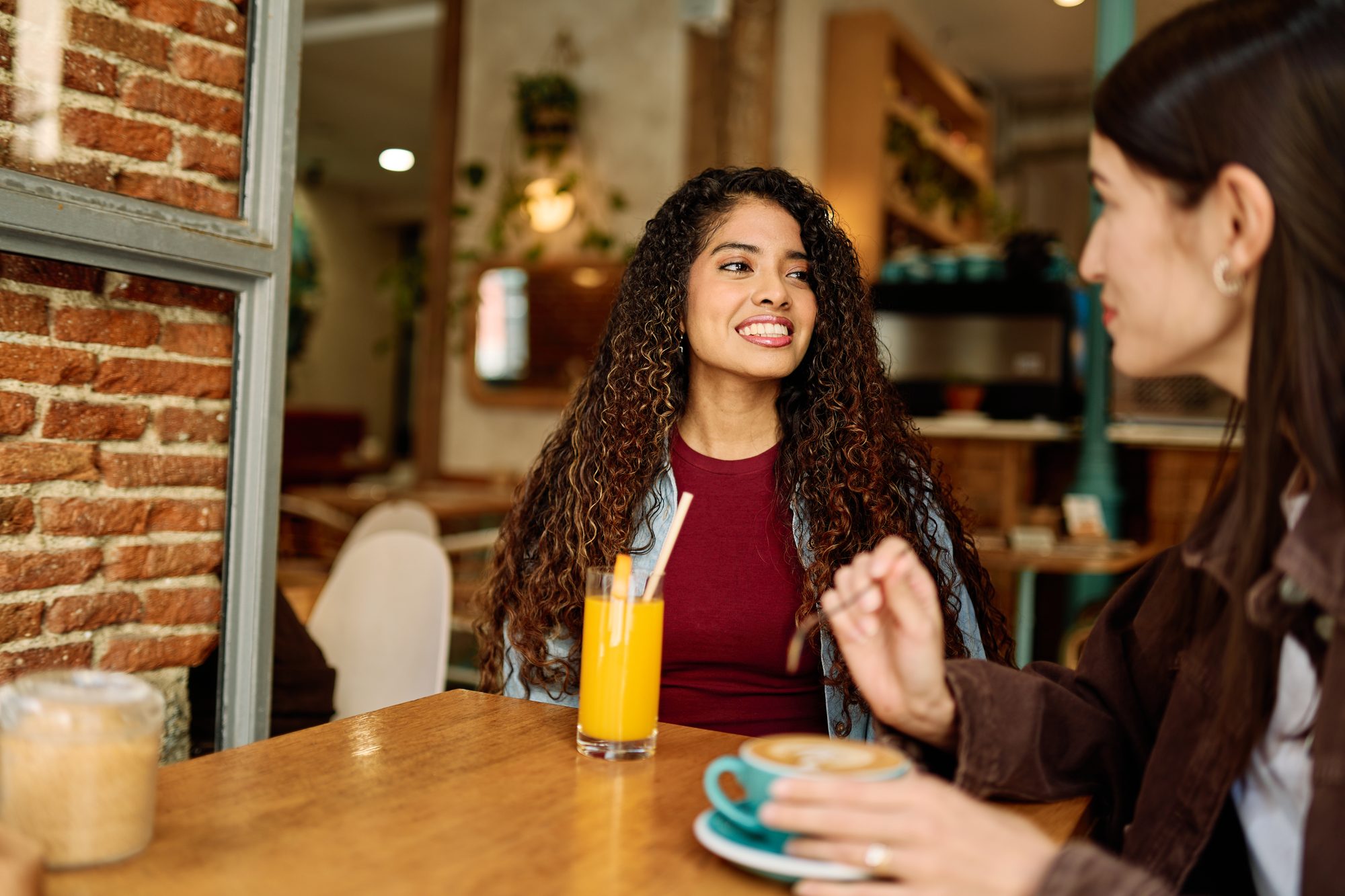 Two friends chatting over coffee and juice in a cozy urban cafe during a relaxed daytime meetup