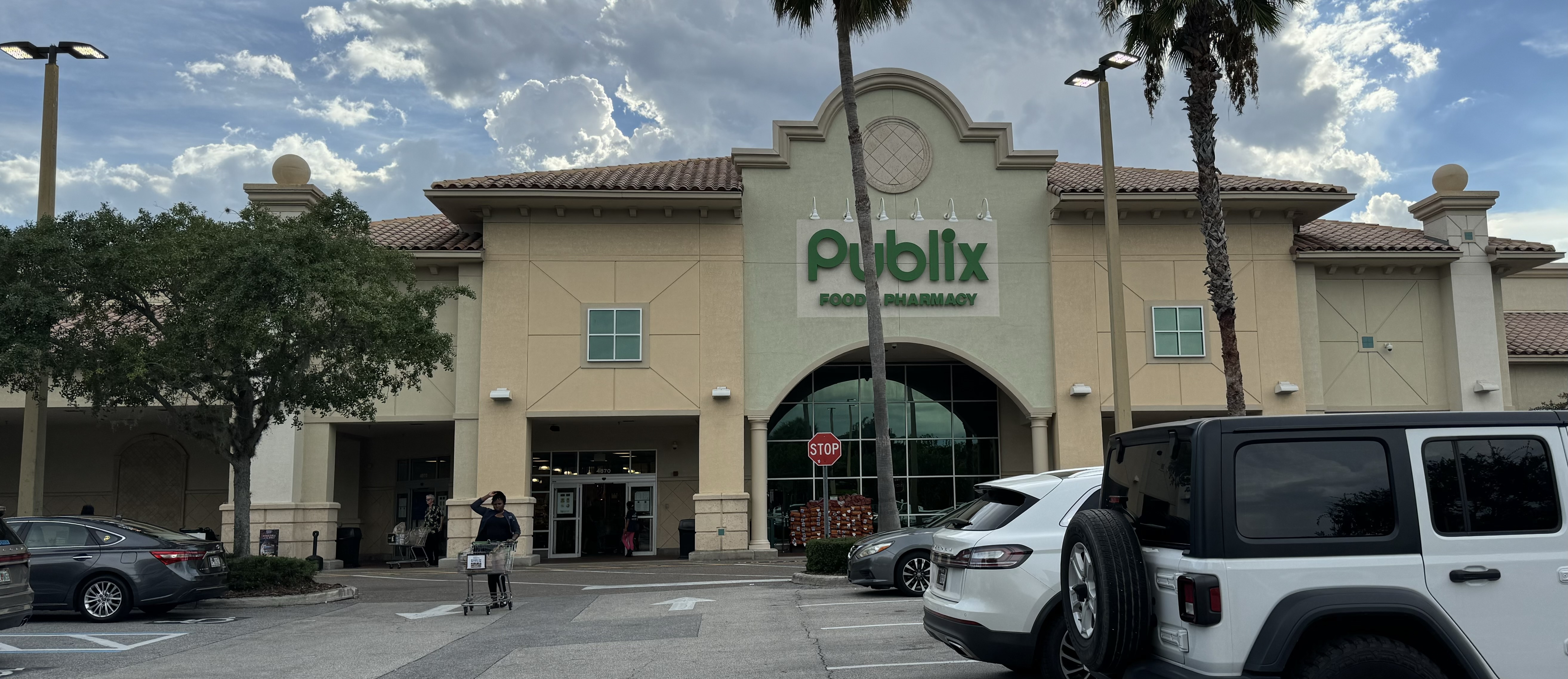 Exterior of a Publix Food and Pharmacy store with palm trees and a parking lot.
