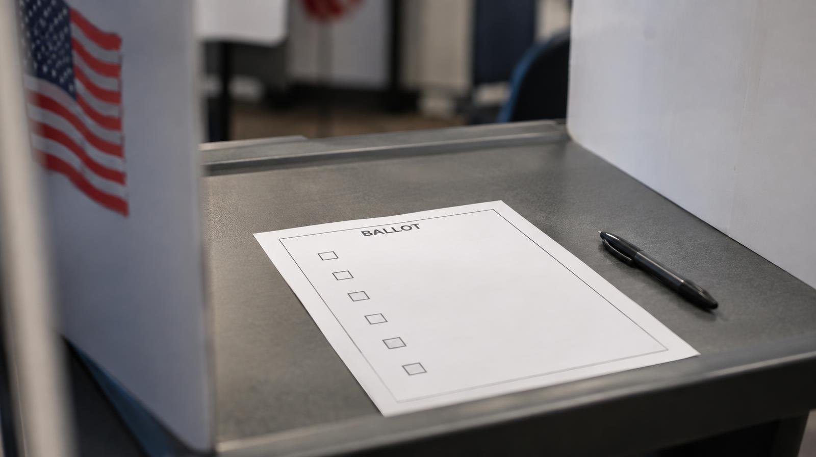 A blank paper ballot on a flat surface with a pen resting beside it.