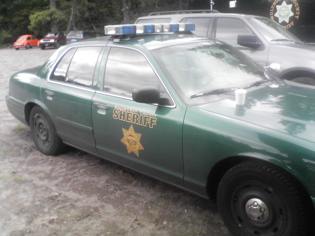 Green sheriff's office patrol car with star badge parked on gravel.