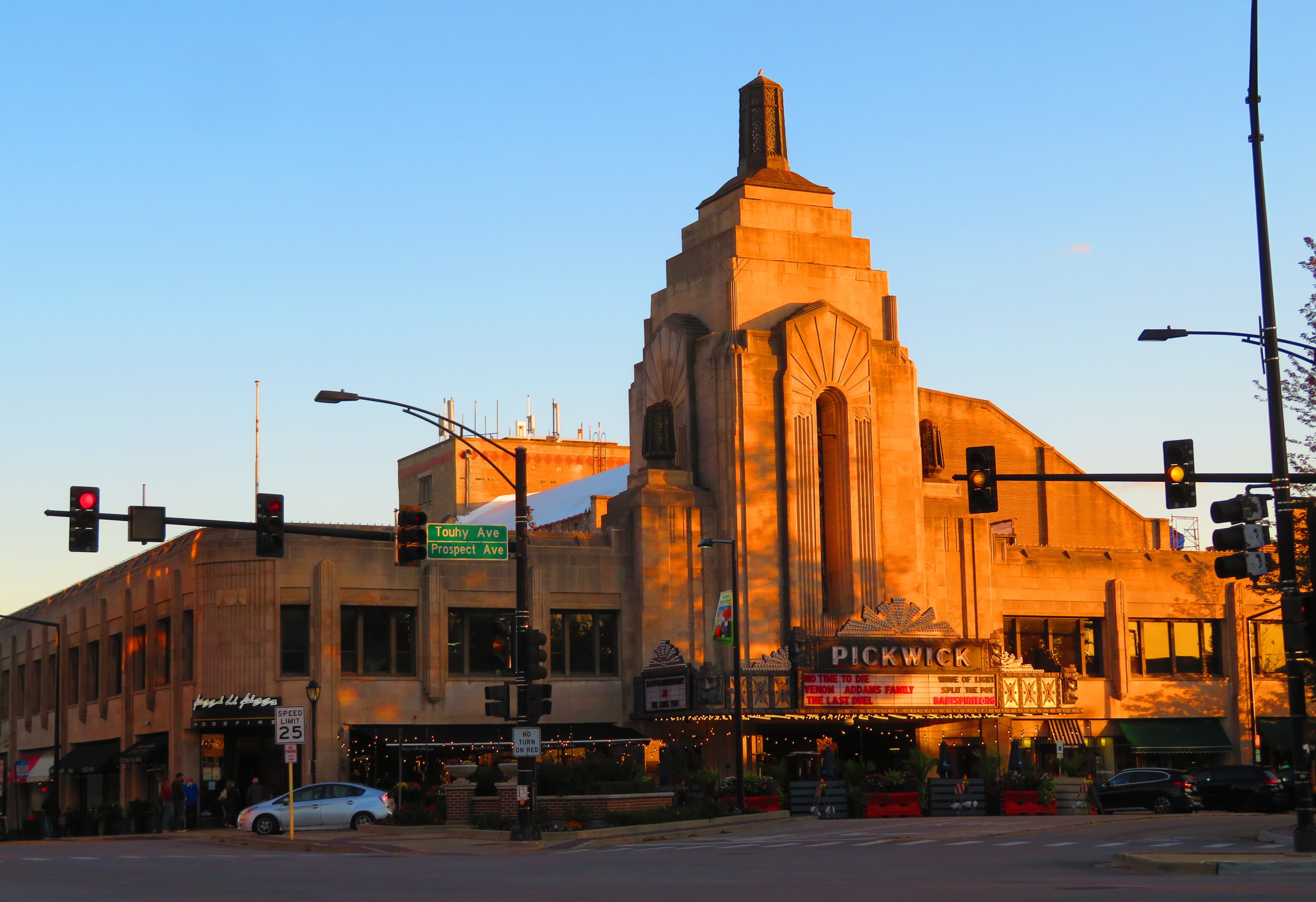 Art Deco theater building with tall tower and marquee sign bathed in golden evening light.