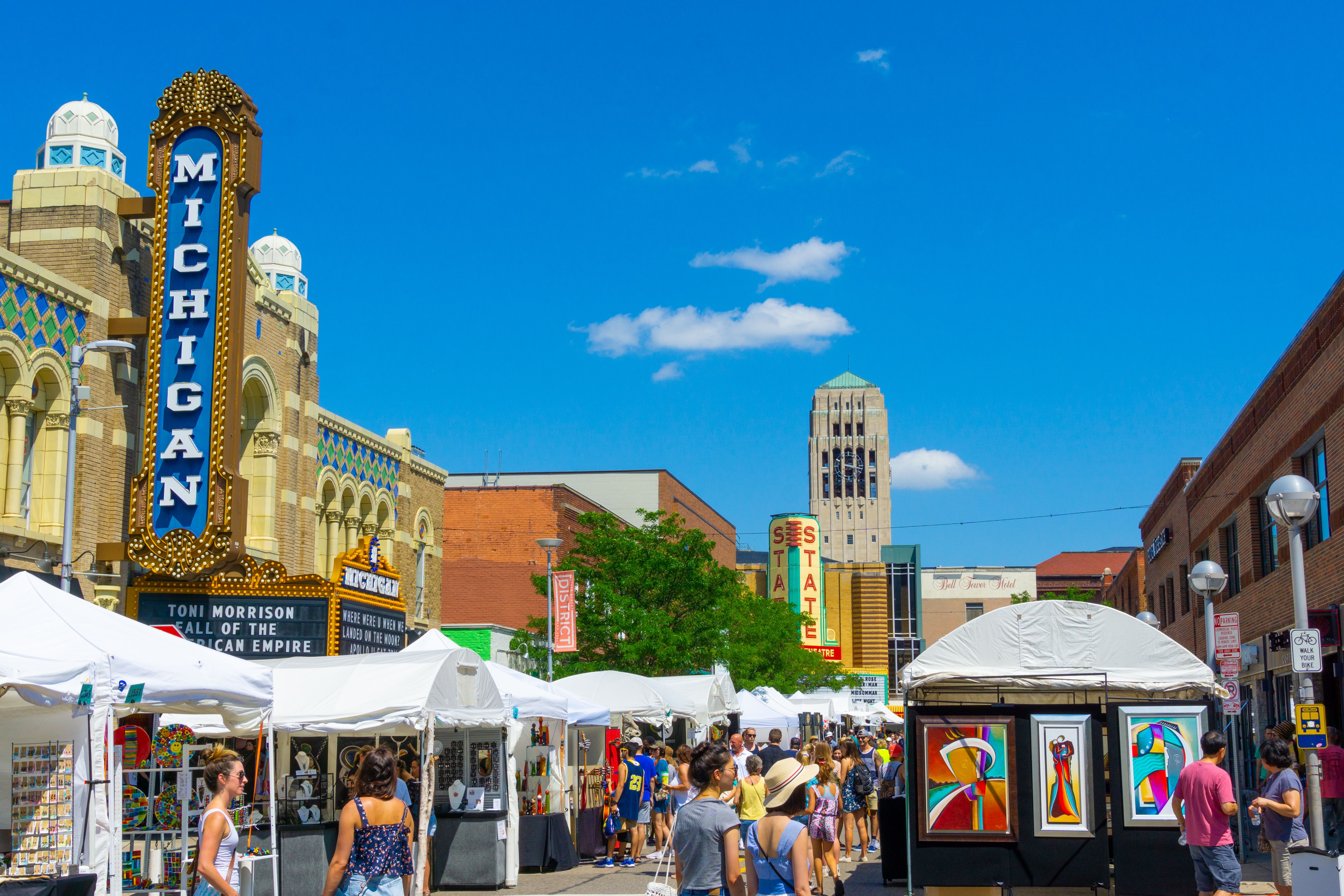 Crowds and white vendor tents fill Liberty Street in downtown Ann Arbor on a sunny day.