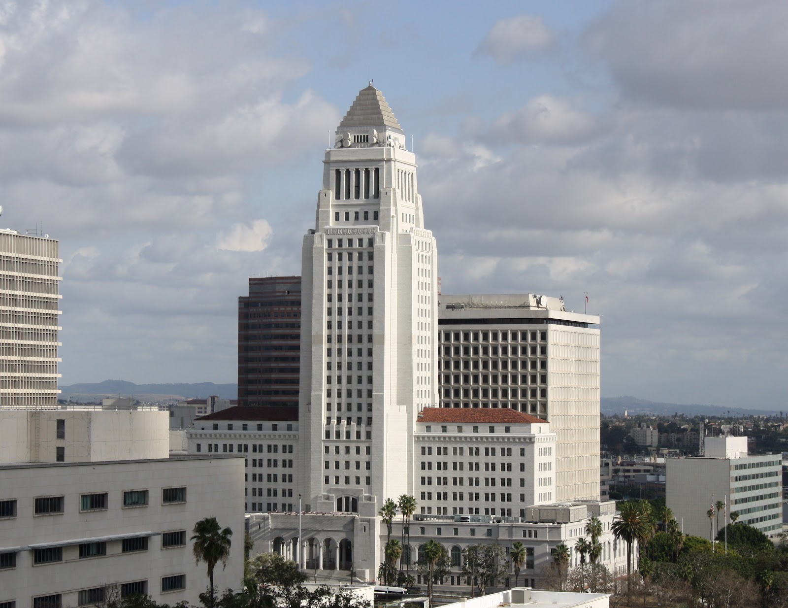 White Art Deco city hall tower rising above downtown Los Angeles buildings.