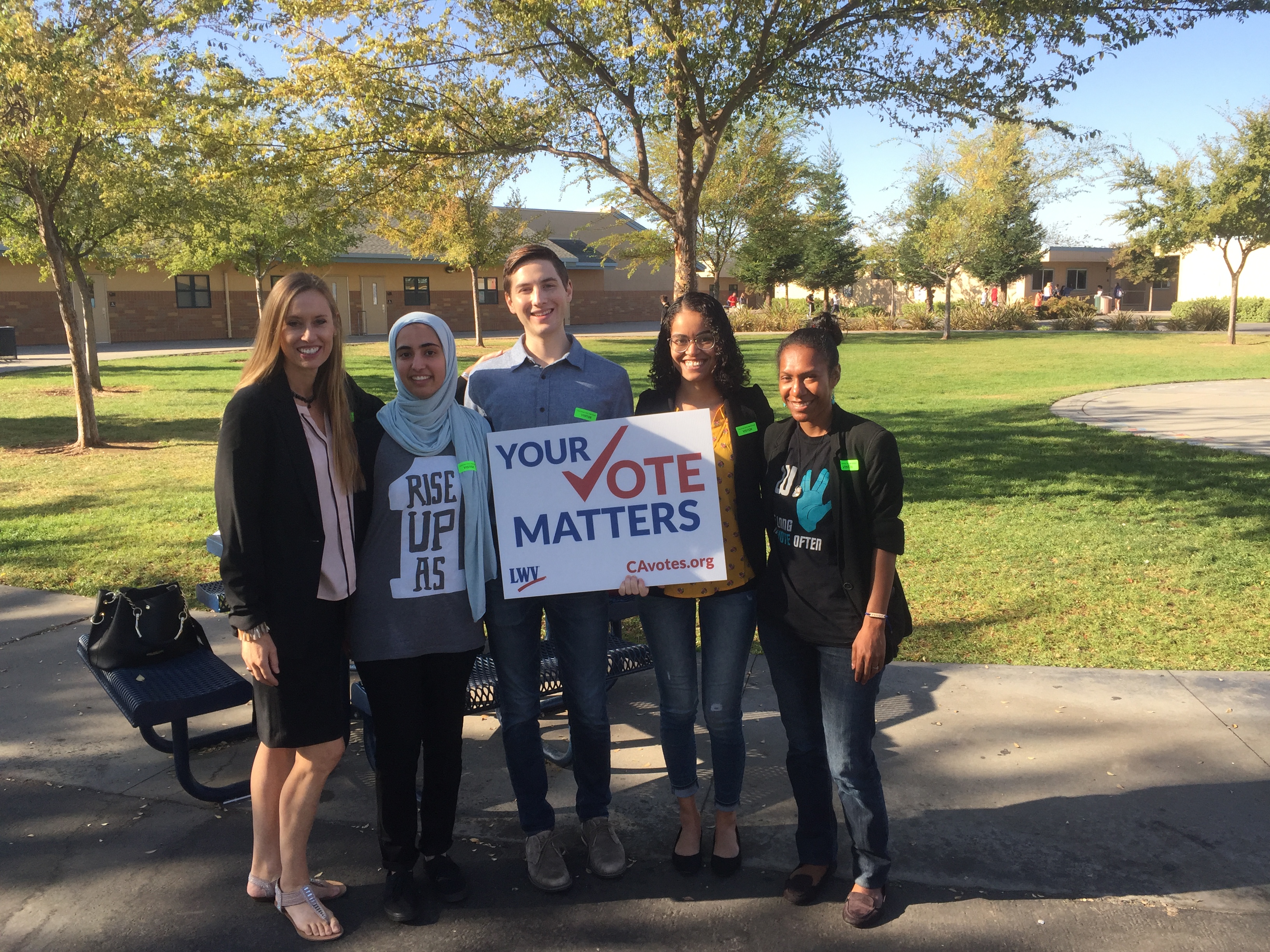 Group of people outdoors holding a sign that reads Your Vote Matters at a voter registration event.