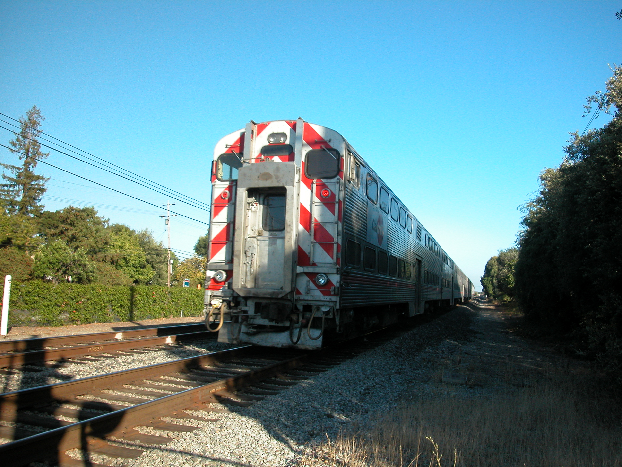 Rear of a passenger train on tracks with red and white chevron safety markings.