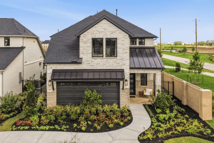 Home with black roof and brick facade with path leading up to it.
