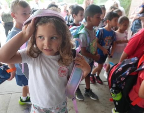 A young girl adjusts her pink backpack strap while lining up with other kindergartners outside Brooklands Elementary School during the Kindergarten Jumpstart program.