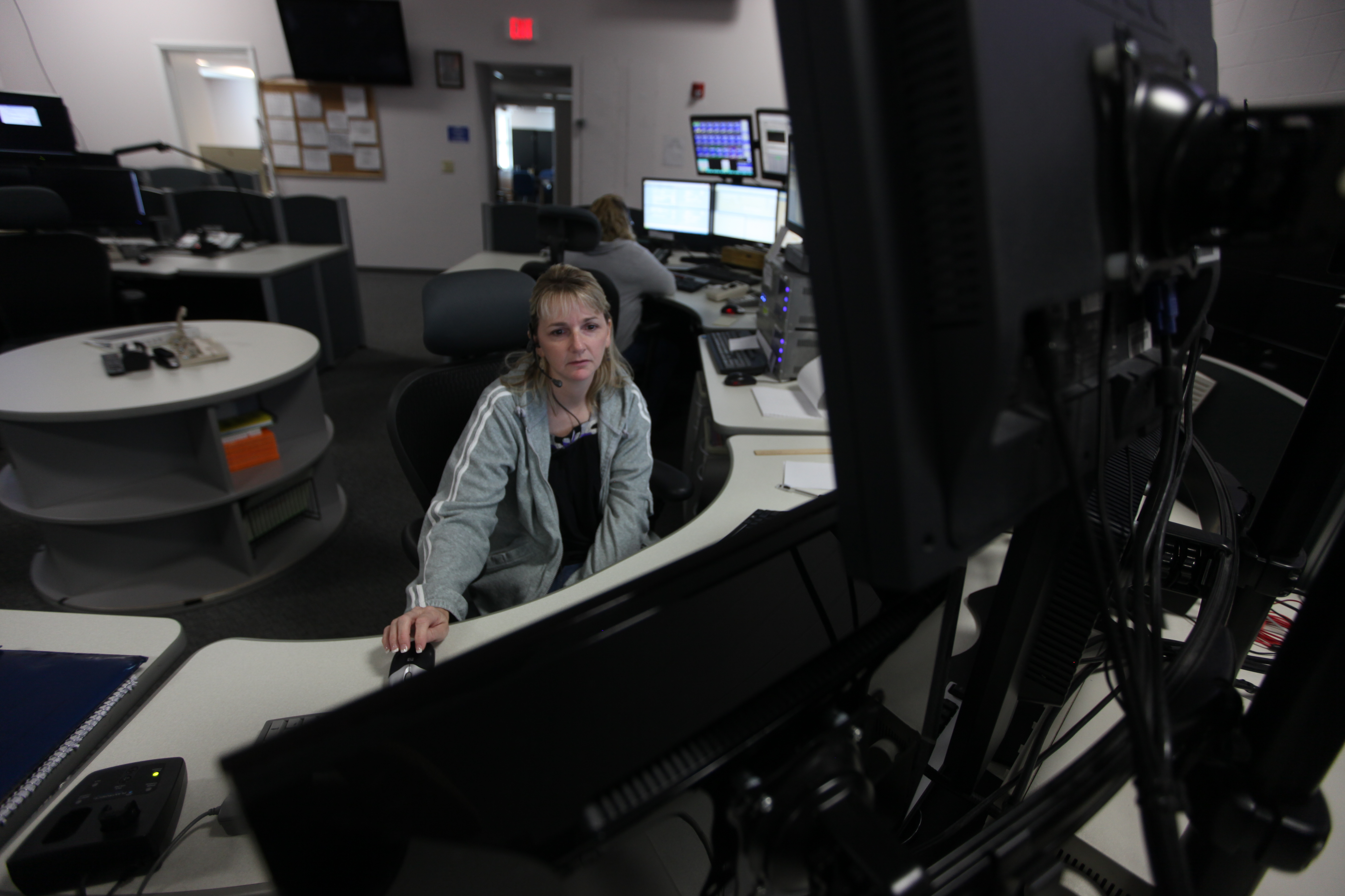 A 911 dispatcher monitors multiple screens at an emergency communications center workstation.