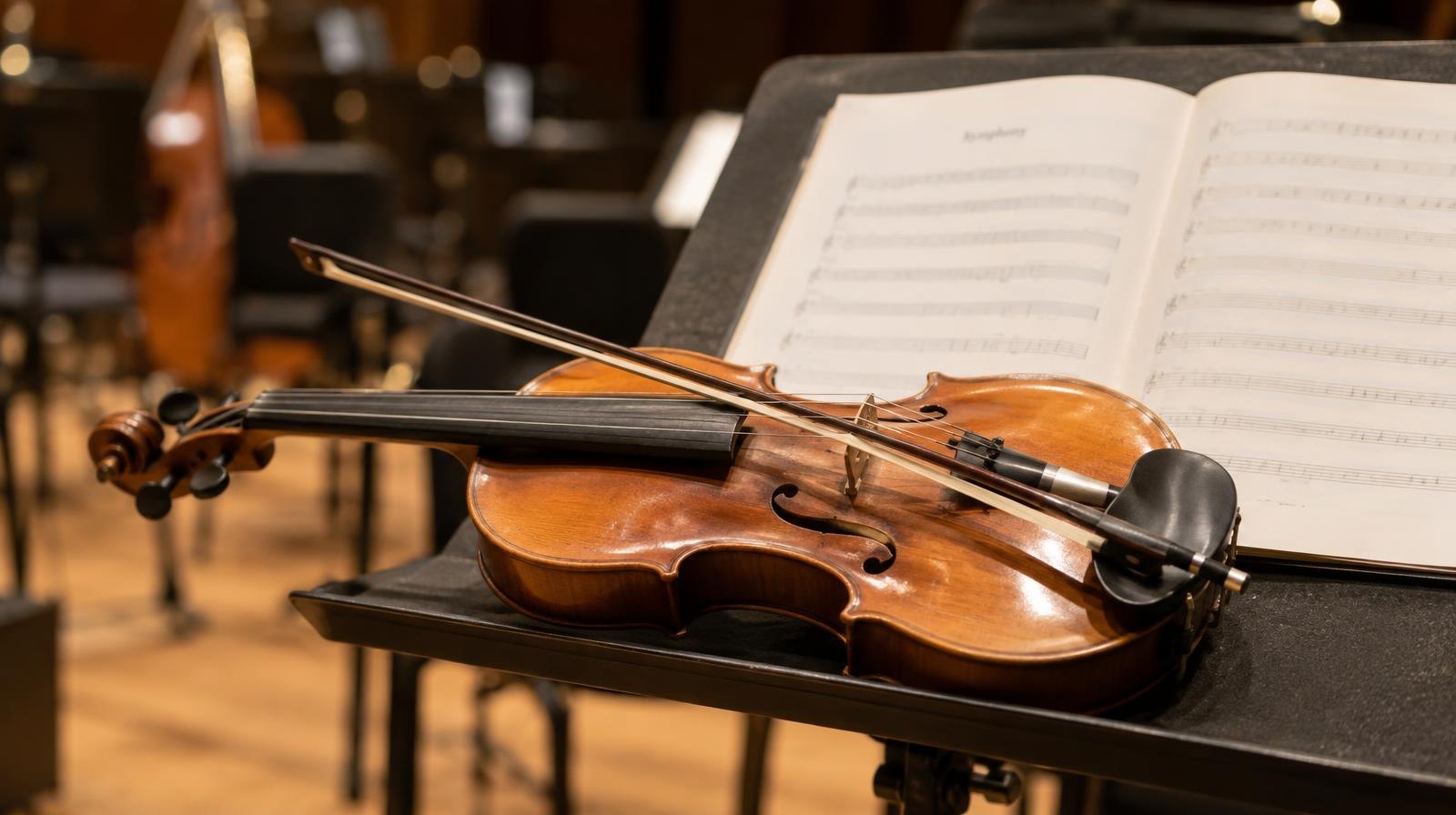 A violin and conductor's baton resting on a music stand with sheet music.