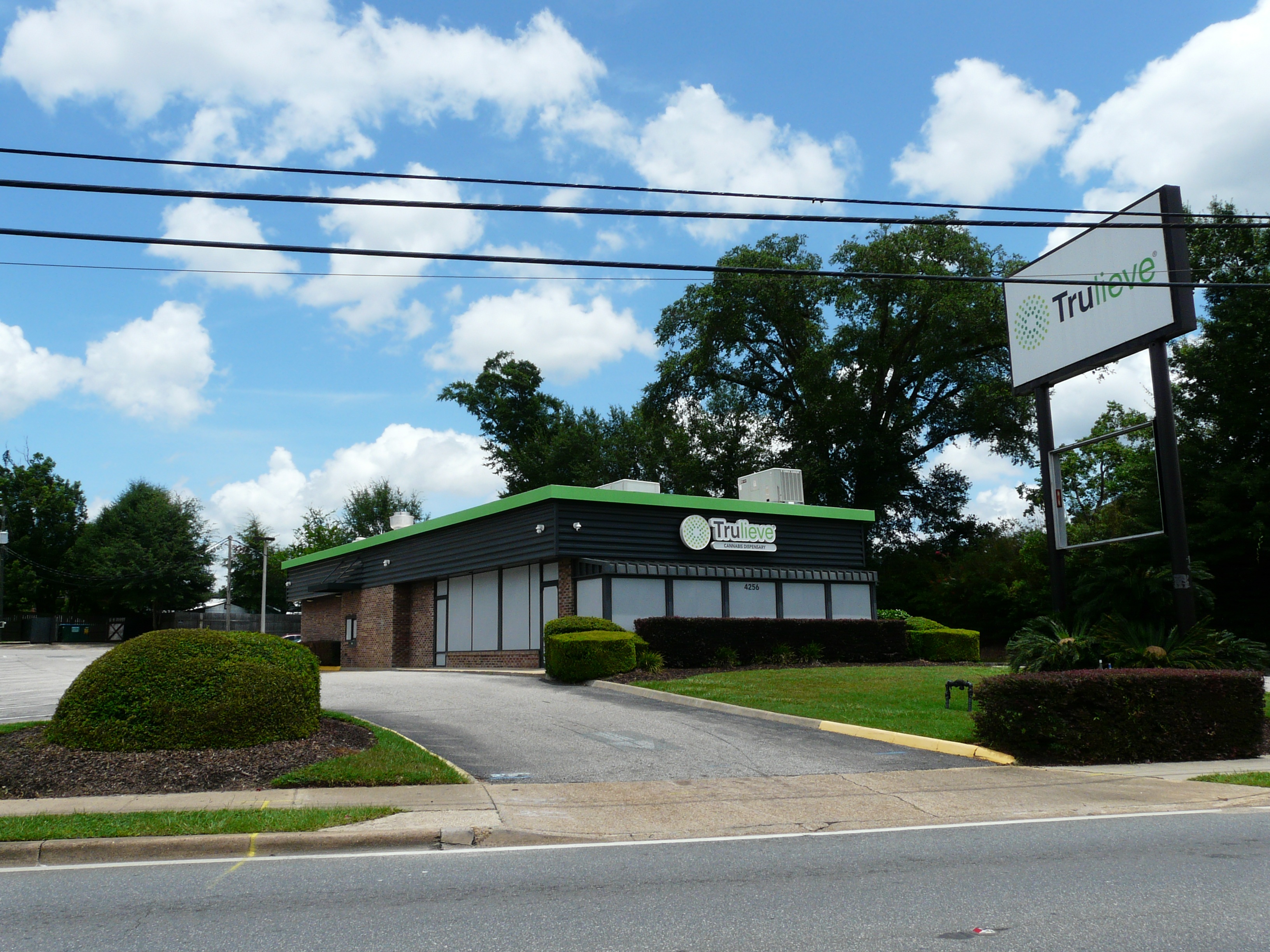 Low-rise commercial building with green trim and Trulieve dispensary signage in a parking lot.