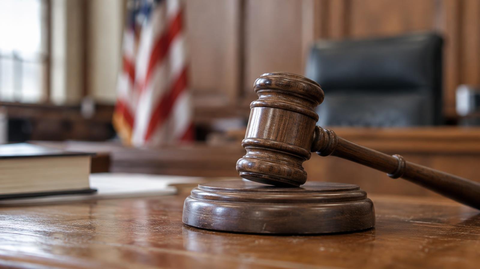 Wooden gavel resting on its sound block on a courtroom bench.