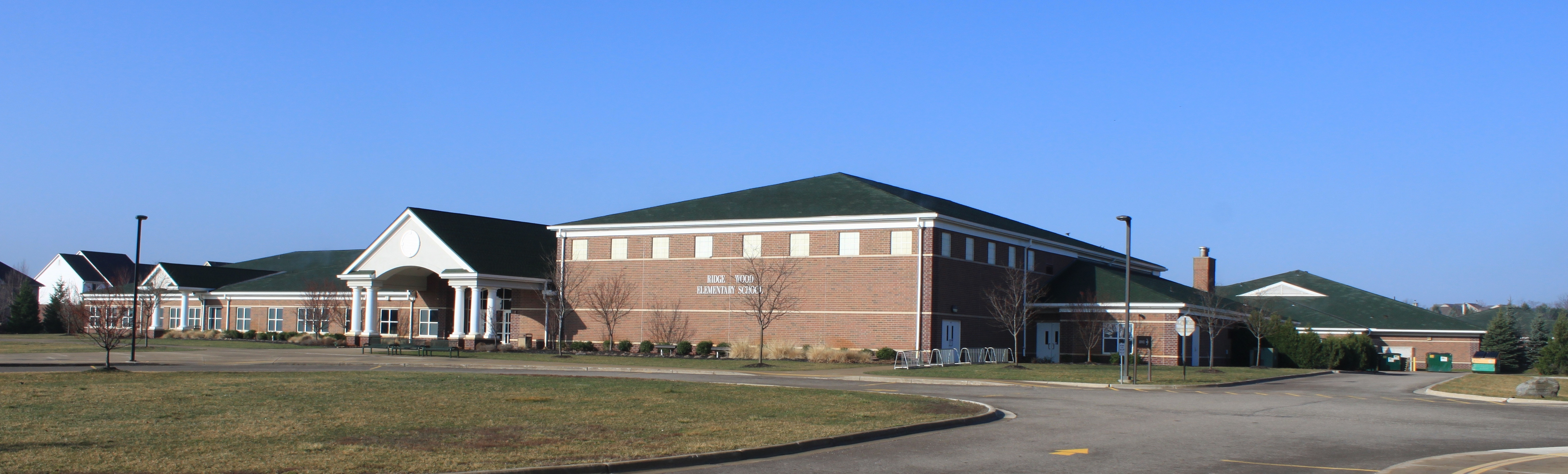 Brick school building with green roof trim and a covered entrance portico.