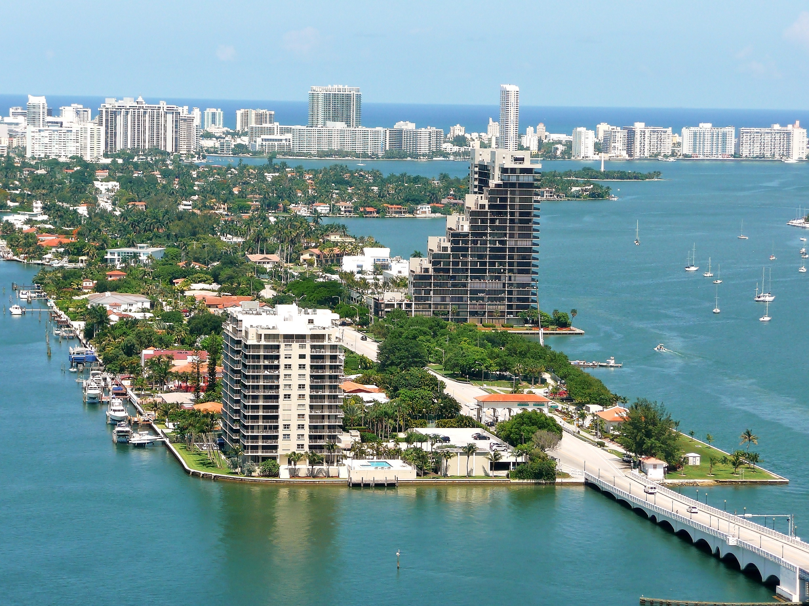 Aerial view of a developed island with waterfront homes and high-rises surrounded by bay waters.