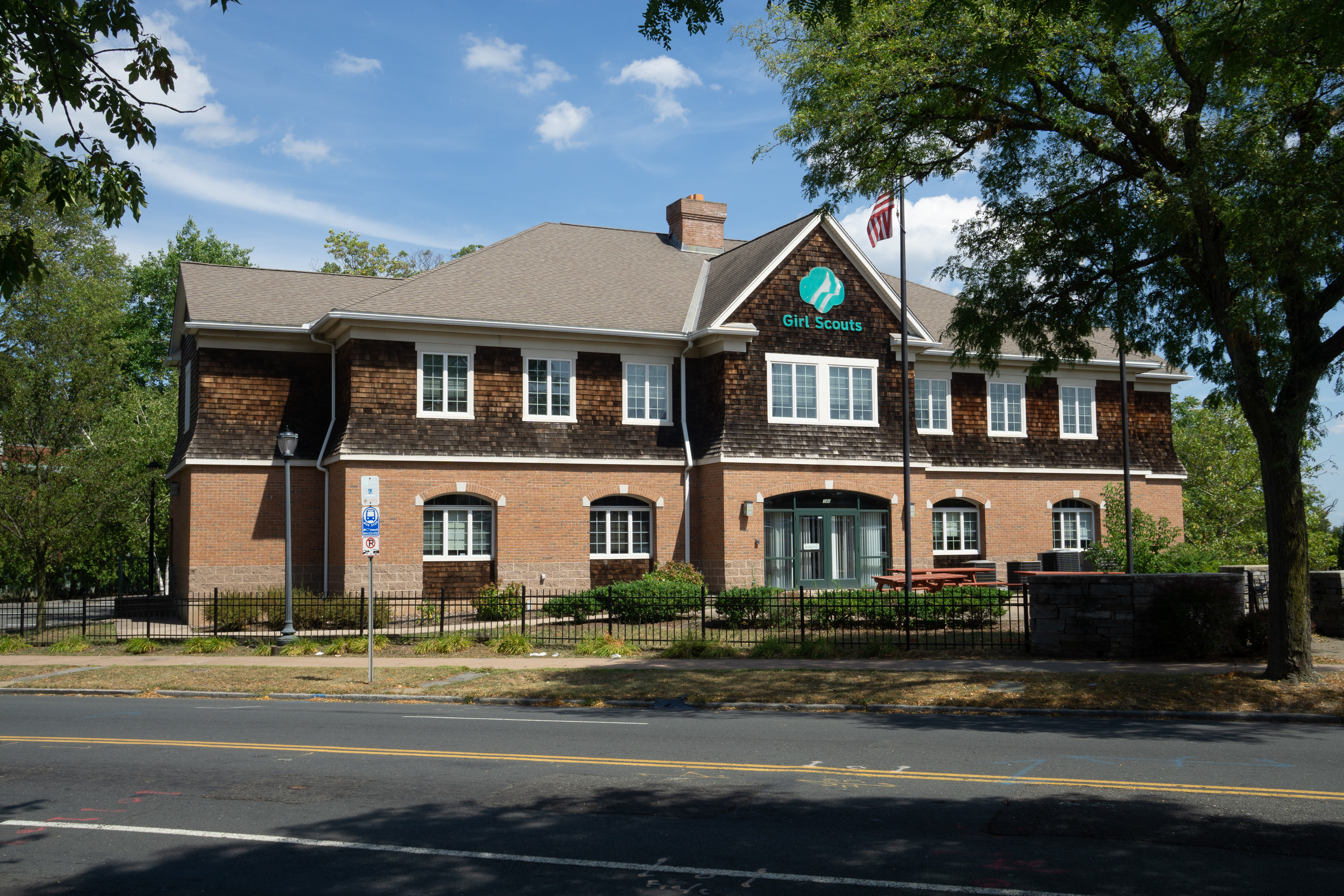 Two-story brick building with a Girl Scouts logo and sign on the facade.