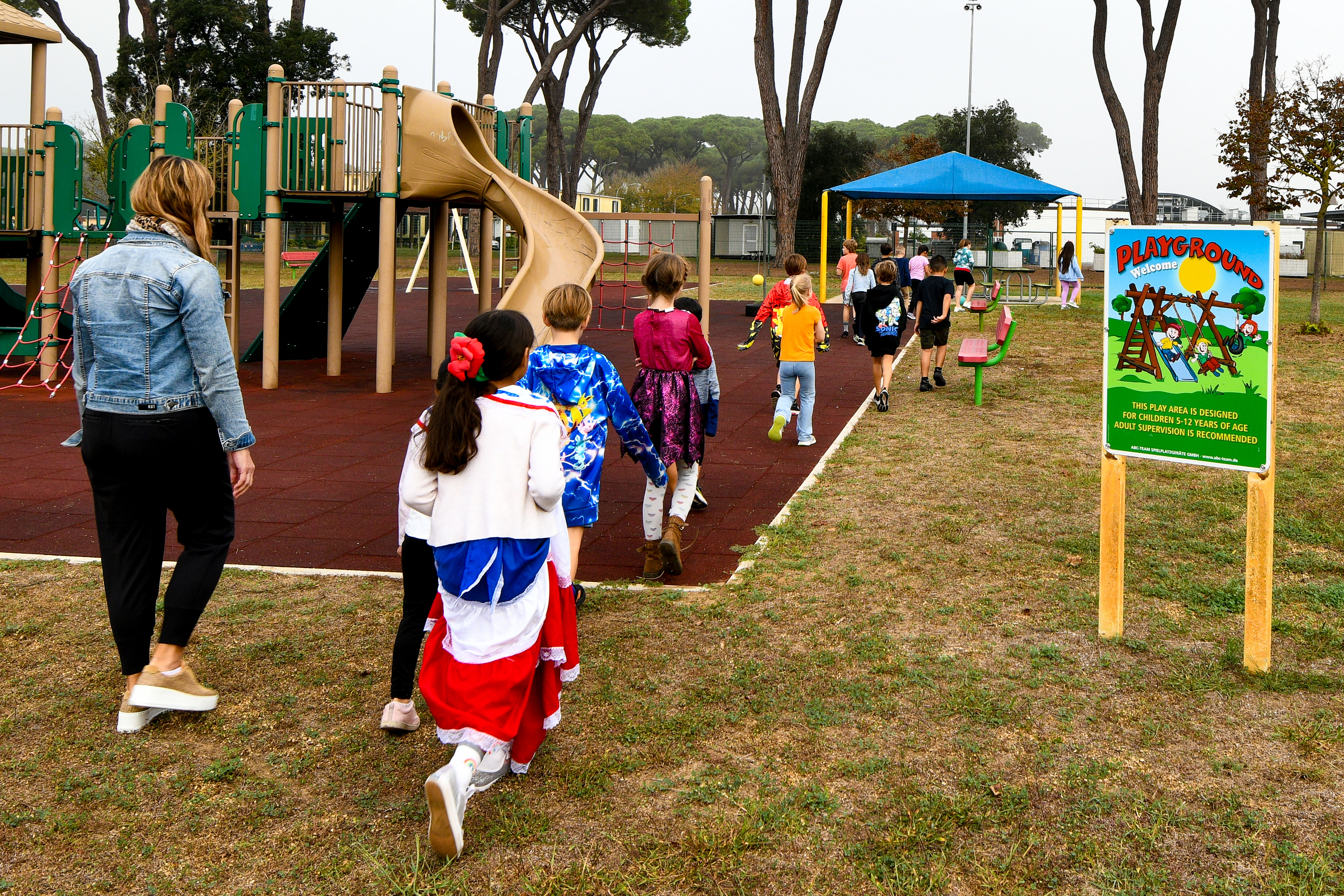 Children walking in a single-file line away from a playground during a fire drill.