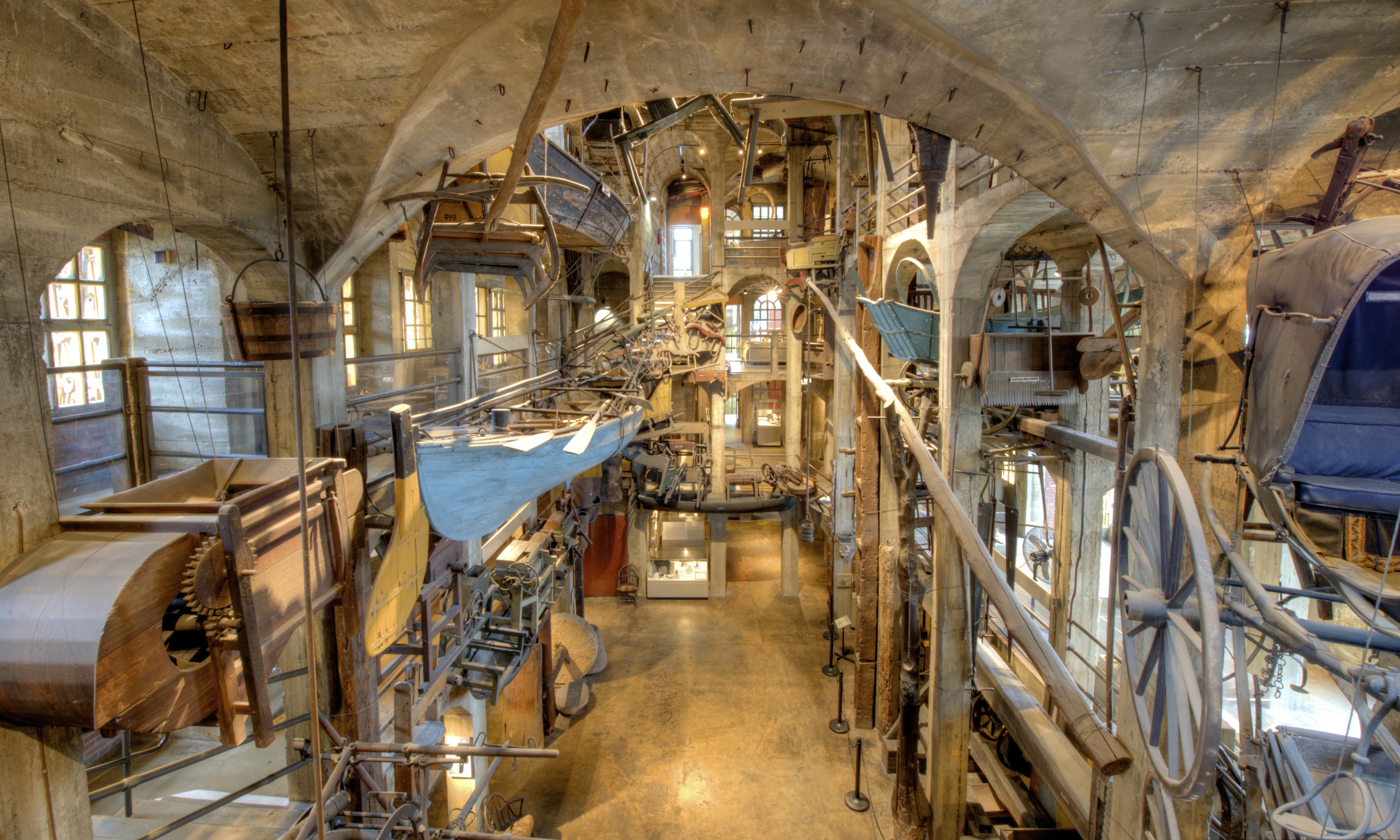 Multi-story museum atrium filled with hanging historic machinery and wooden artifacts.