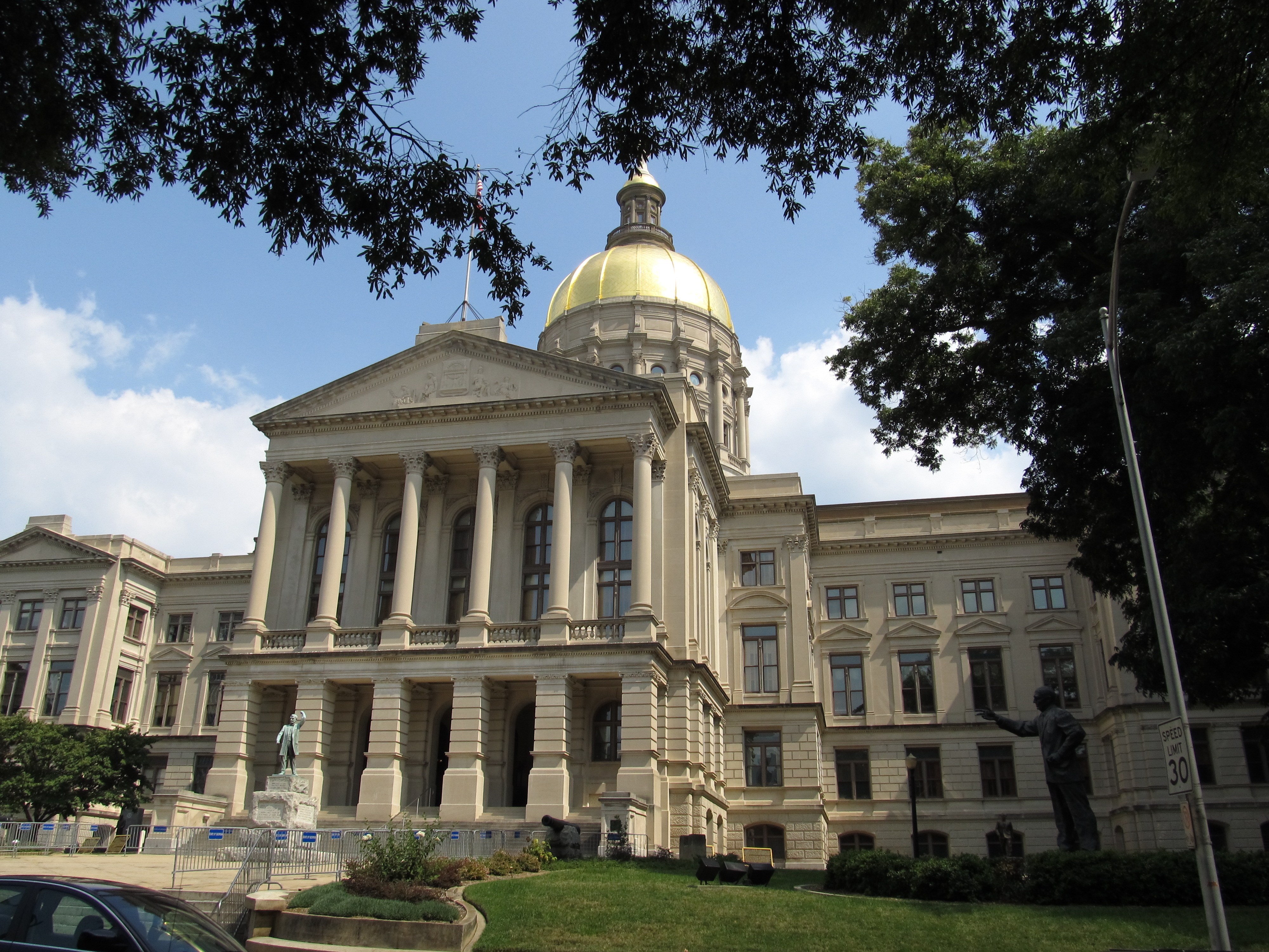 Georgia State Capitol building with gold dome and neoclassical columns, surrounded by trees.