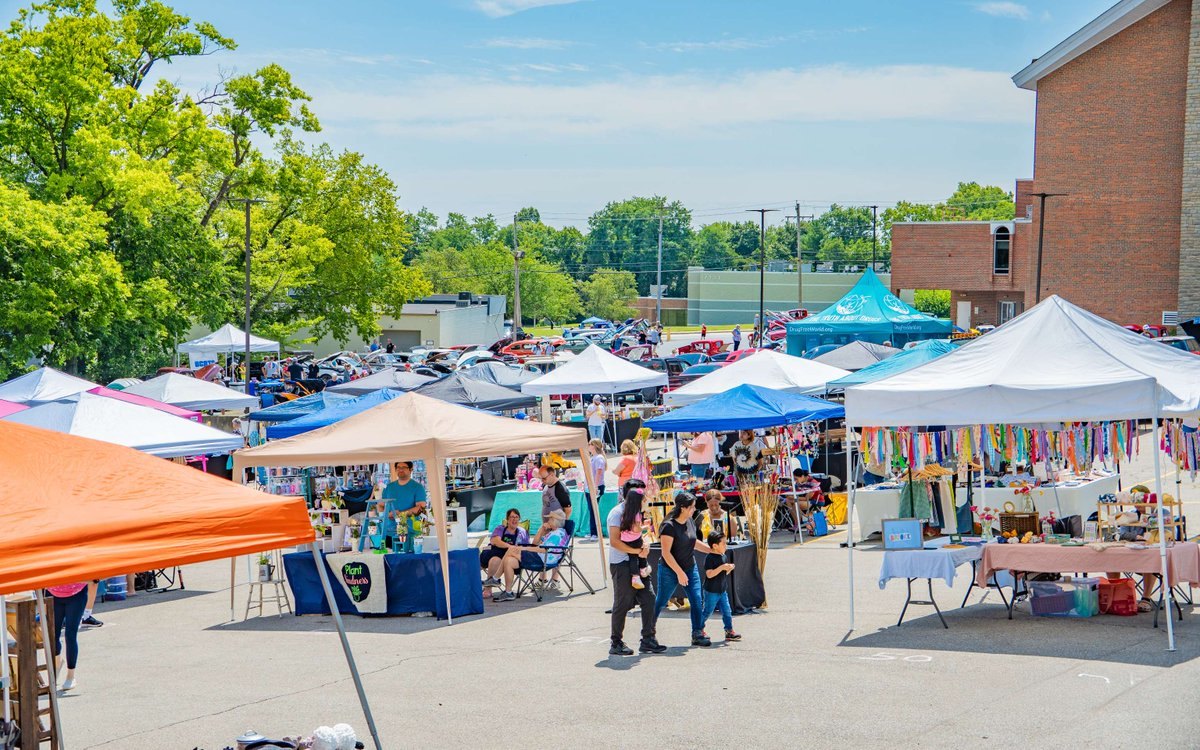 Outdoor festival with colorful pop-up canopy tents and vendor booths, people browsing.
