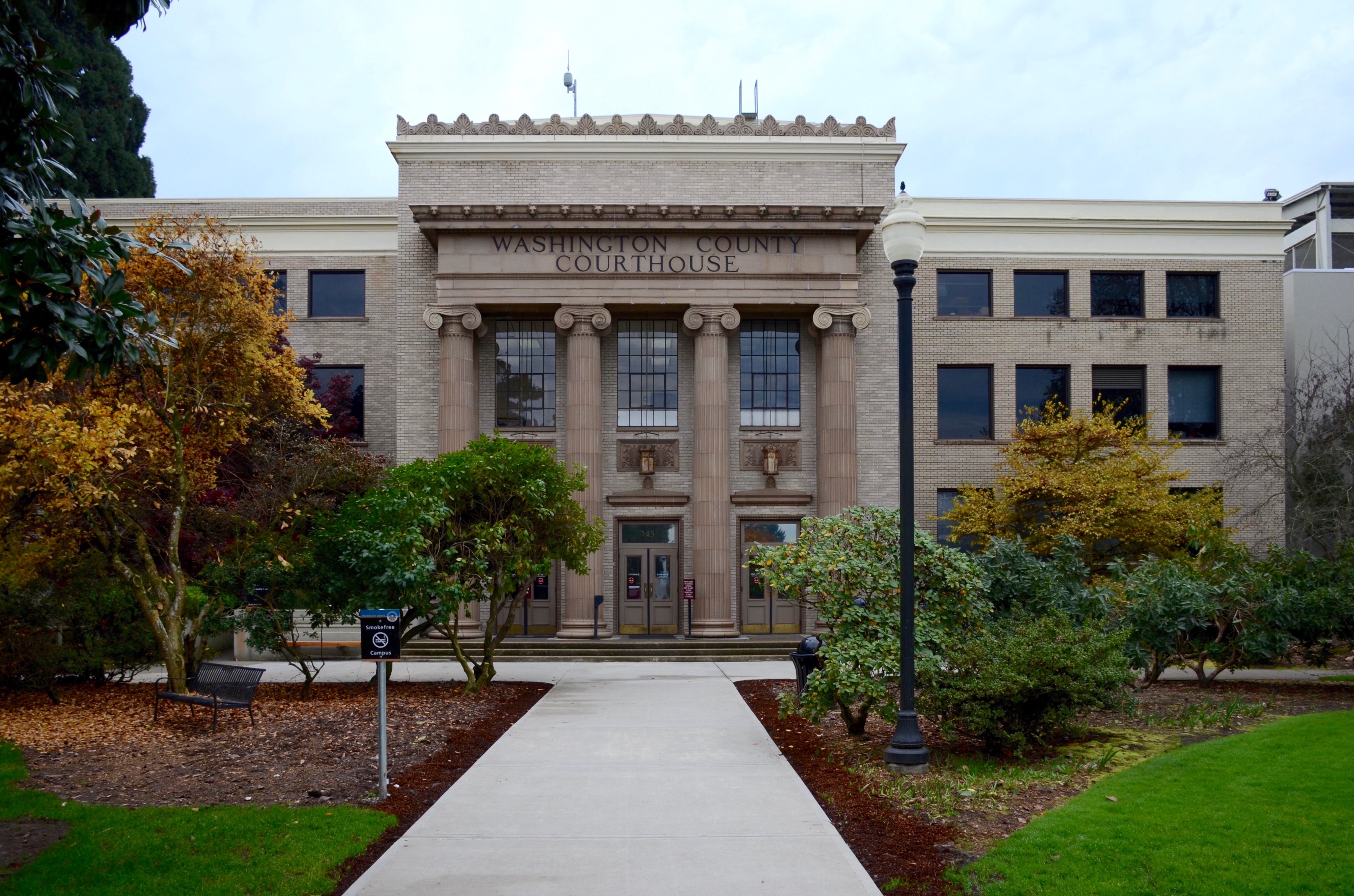 Neoclassical stone courthouse with tall columns and a tree-lined walkway.